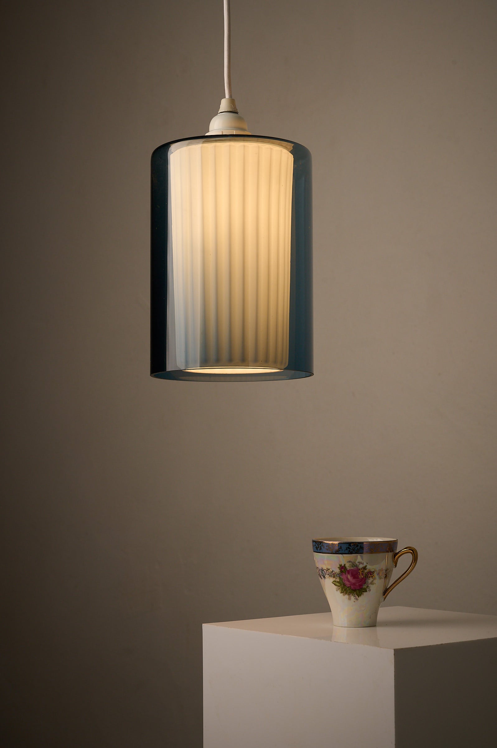 Double Glass Pendant in Blue and Opaline, Europe, 1960s/1970s hanging above a decorative cup.
