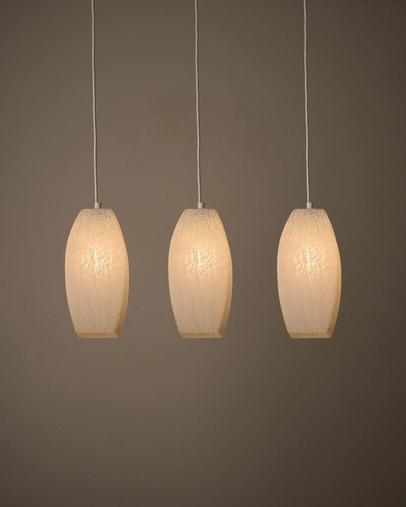 Trio of Ovoid Glass Pendants with Crackle Frosted Pattern, Europe, 1960s/1970s displayed against a minimalist background.