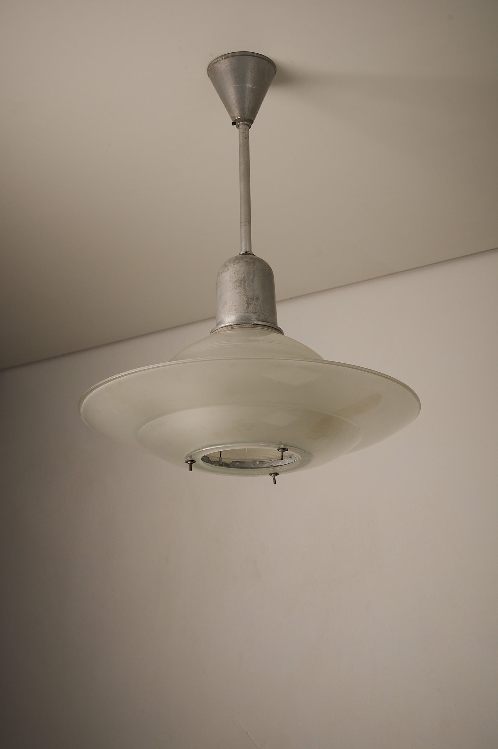 Art Deco Industrial Pendant, 1930s featuring a glass shade with tiered construction and adjustable screws.
