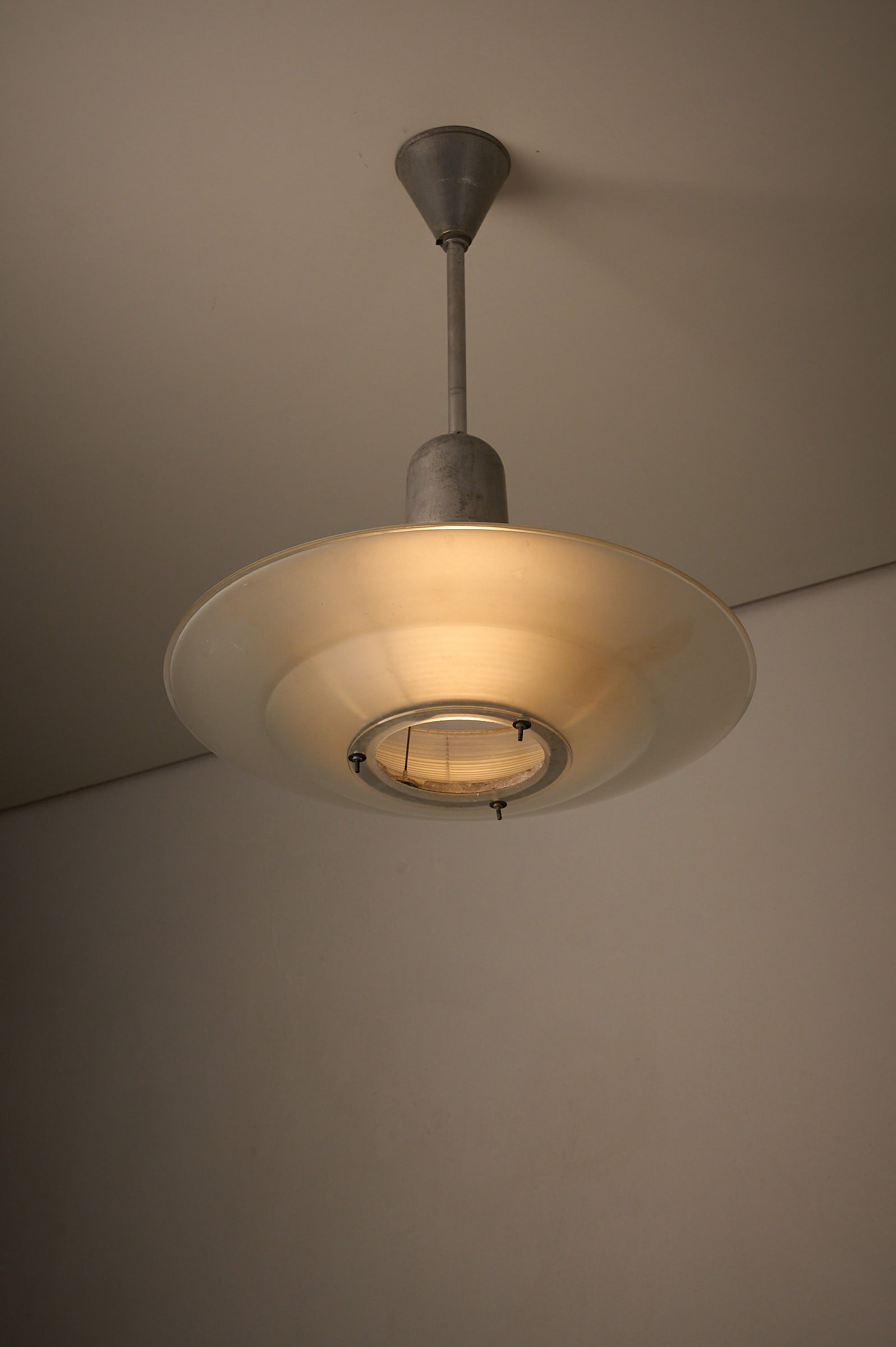 Art Deco Industrial Pendant, 1930s featuring a glass shade with tiered design for optimal light diffusion.