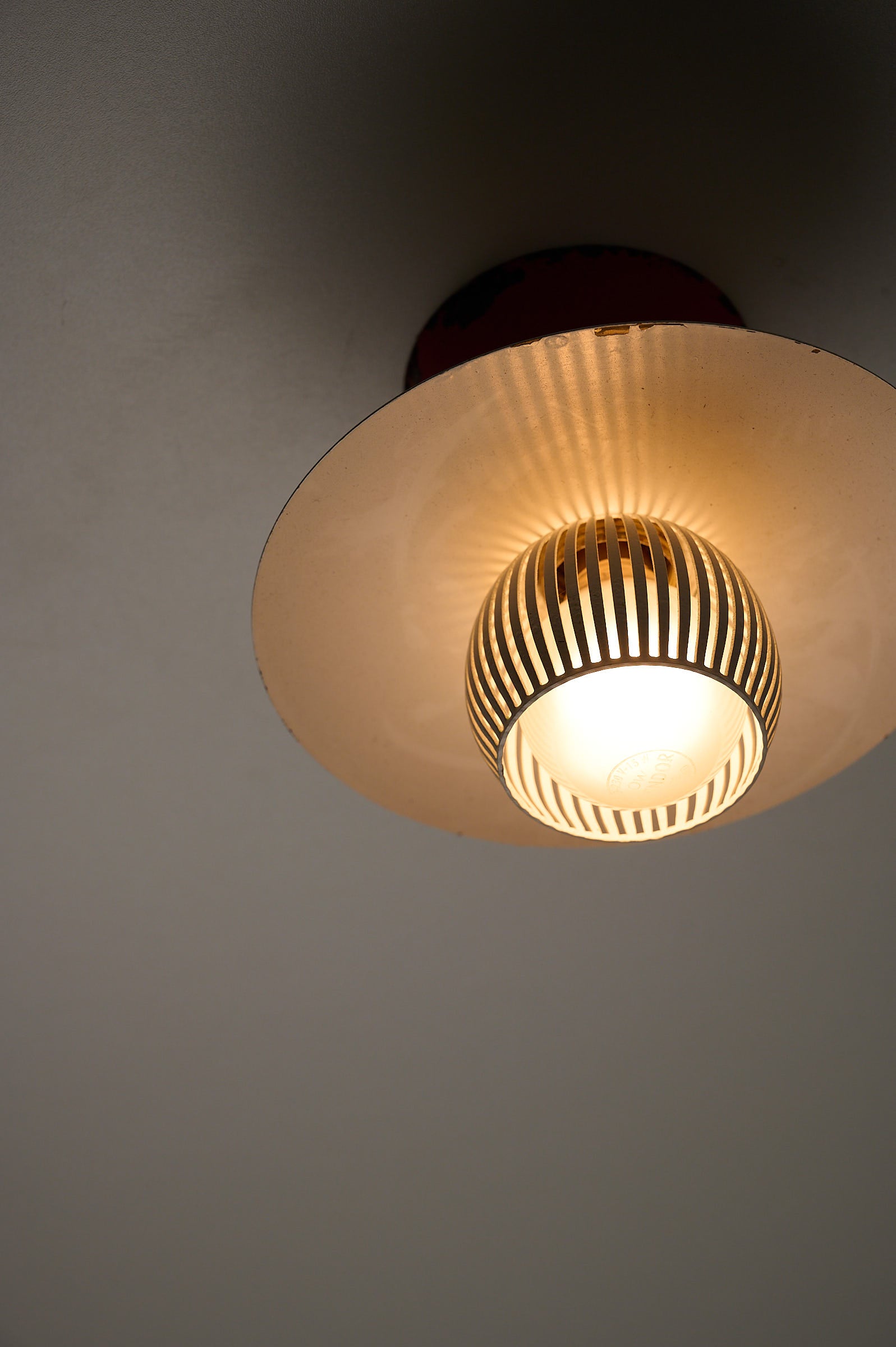 Mid-Century Flush Mount Ceiling Lamp with White Slatted Diffuser illuminating with soft light and unique slatted design.