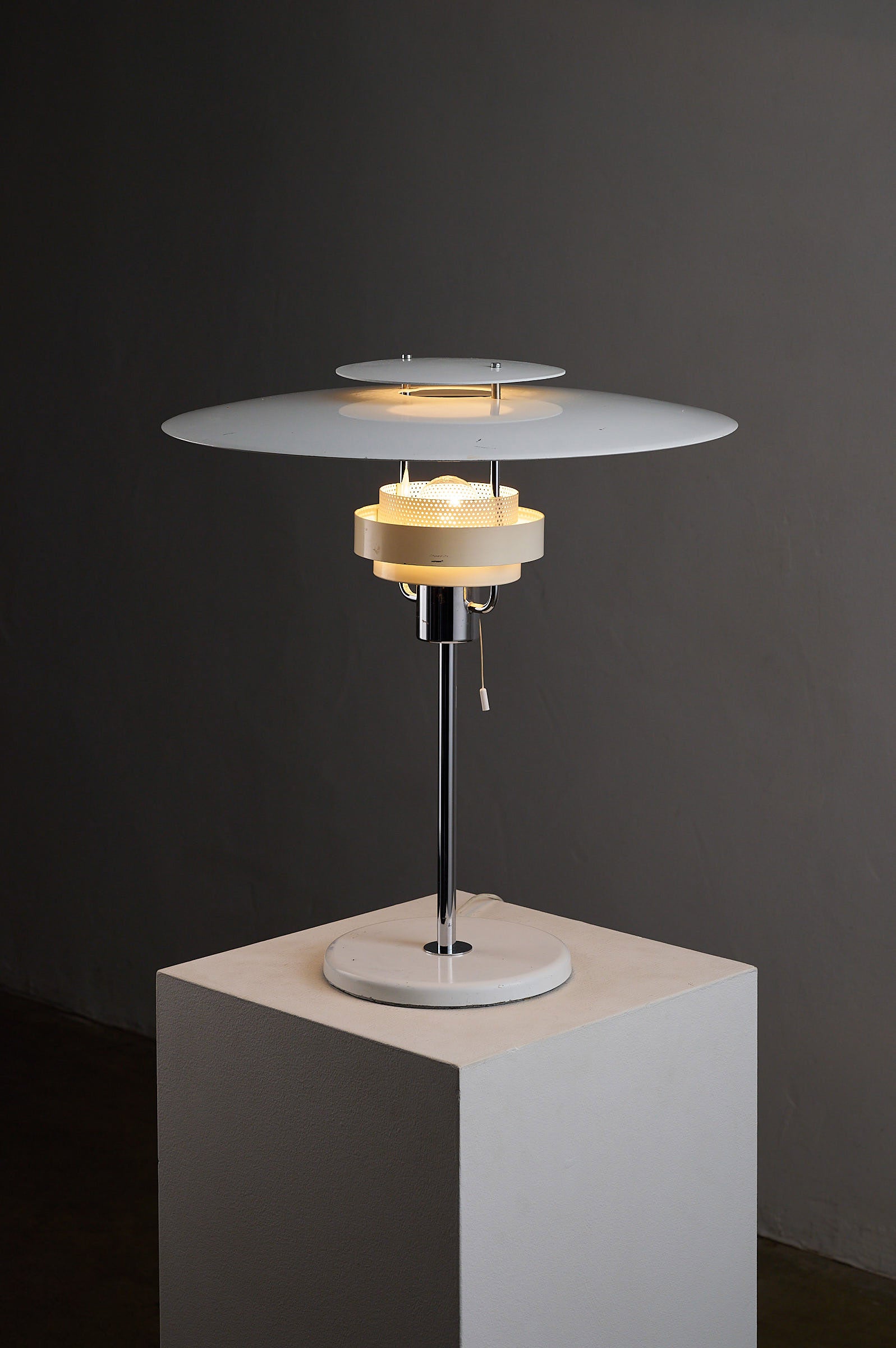 Aurora' White Lacquered Metal Table Lamp by Olle Anderson for Boréns on display, showcasing its elegant design and glow.