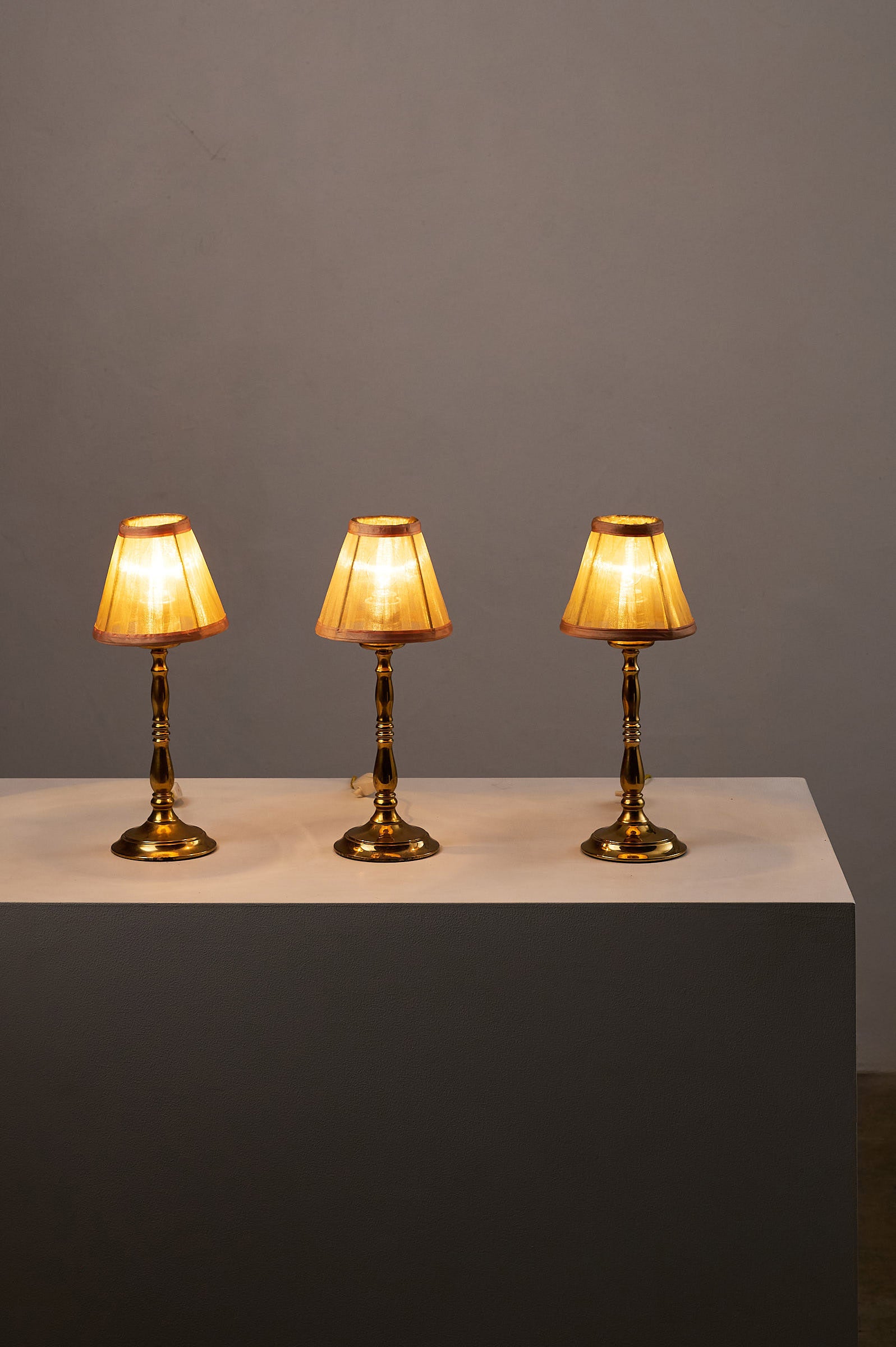 Hollywood Regency Brass Table Lamps, Europe, 1970s displayed on a white pedestal with warm lighting.