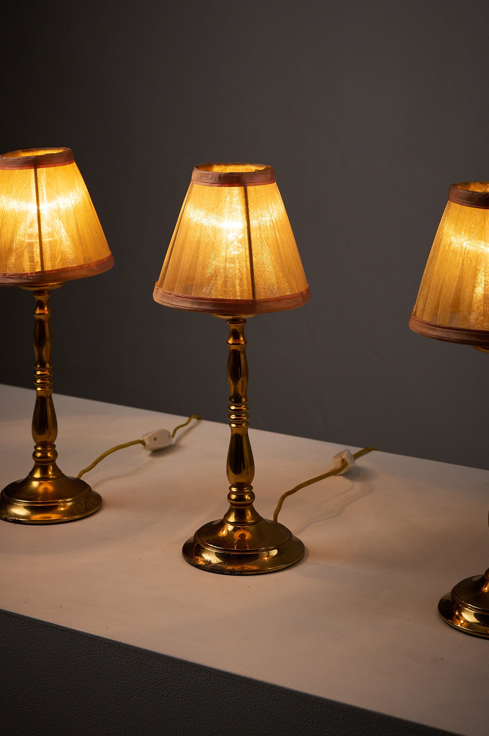 Hollywood Regency Brass Table Lamps, Europe, 1970s with pleated shades lit up on a white table.