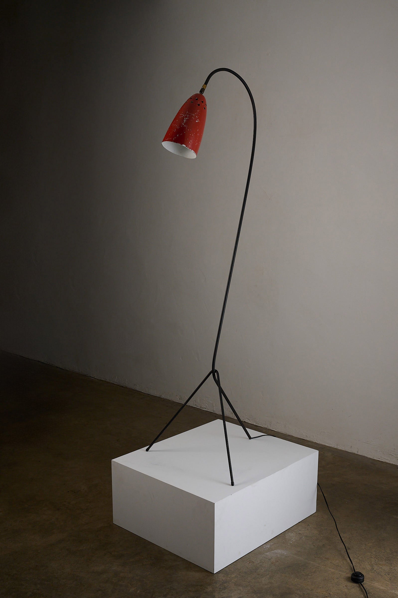 'Grasshopper' Floor Lamp, The Netherlands, 1950s with a sleek black tripod and vibrant red shade.