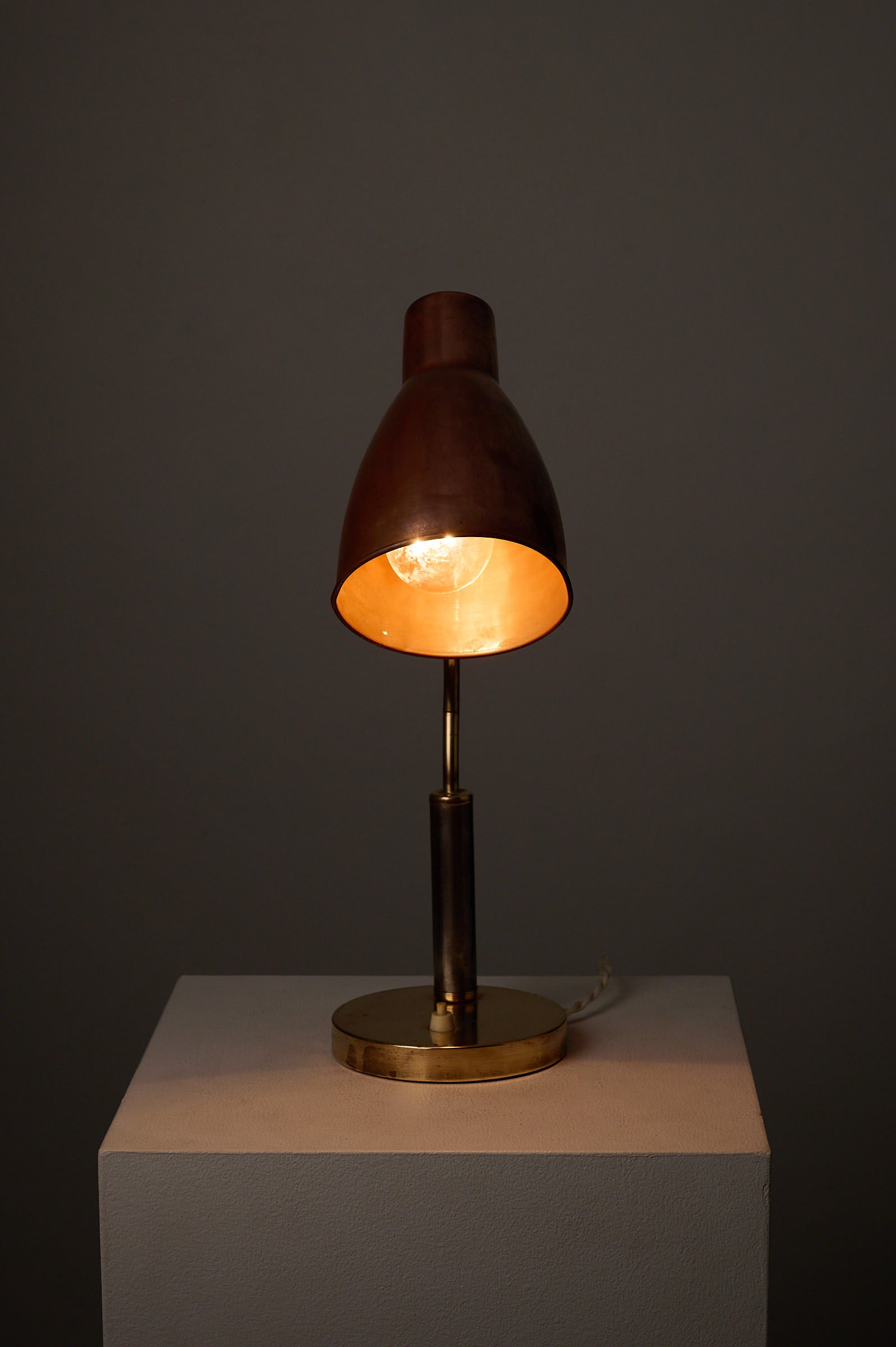 Mid-Century Modern Copper & Brass Desk Lamp, Europe, 1950s on a white pedestal with warm lighting.