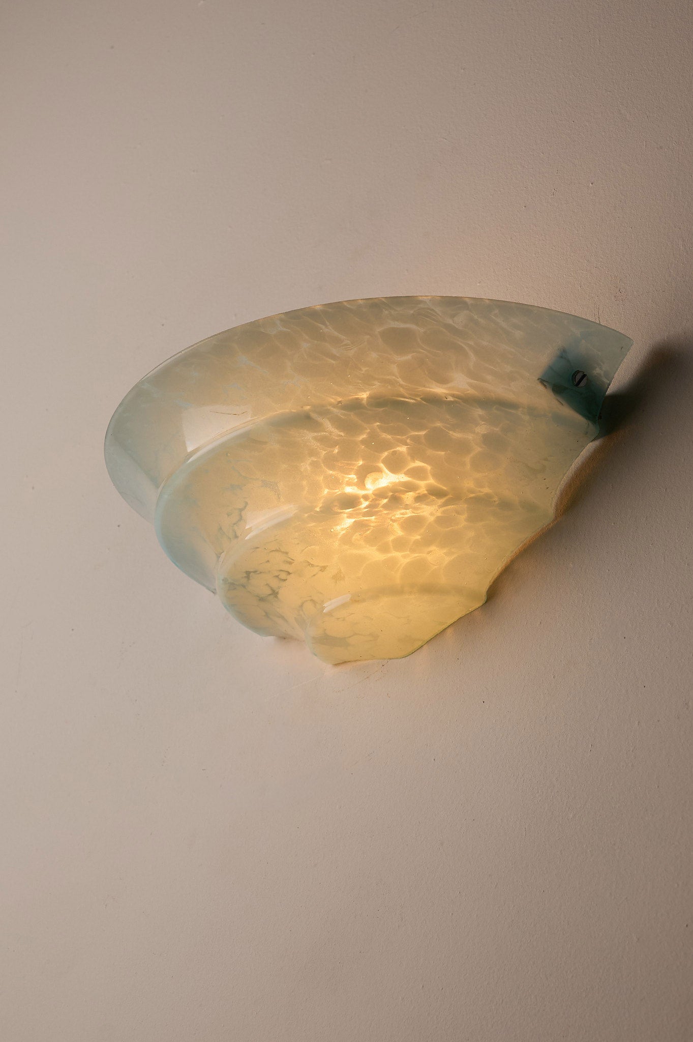 1940s Mid-Century Blue Marbled Glass Shell Wall Sconce illuminating a wall with its unique shell-shaped design.