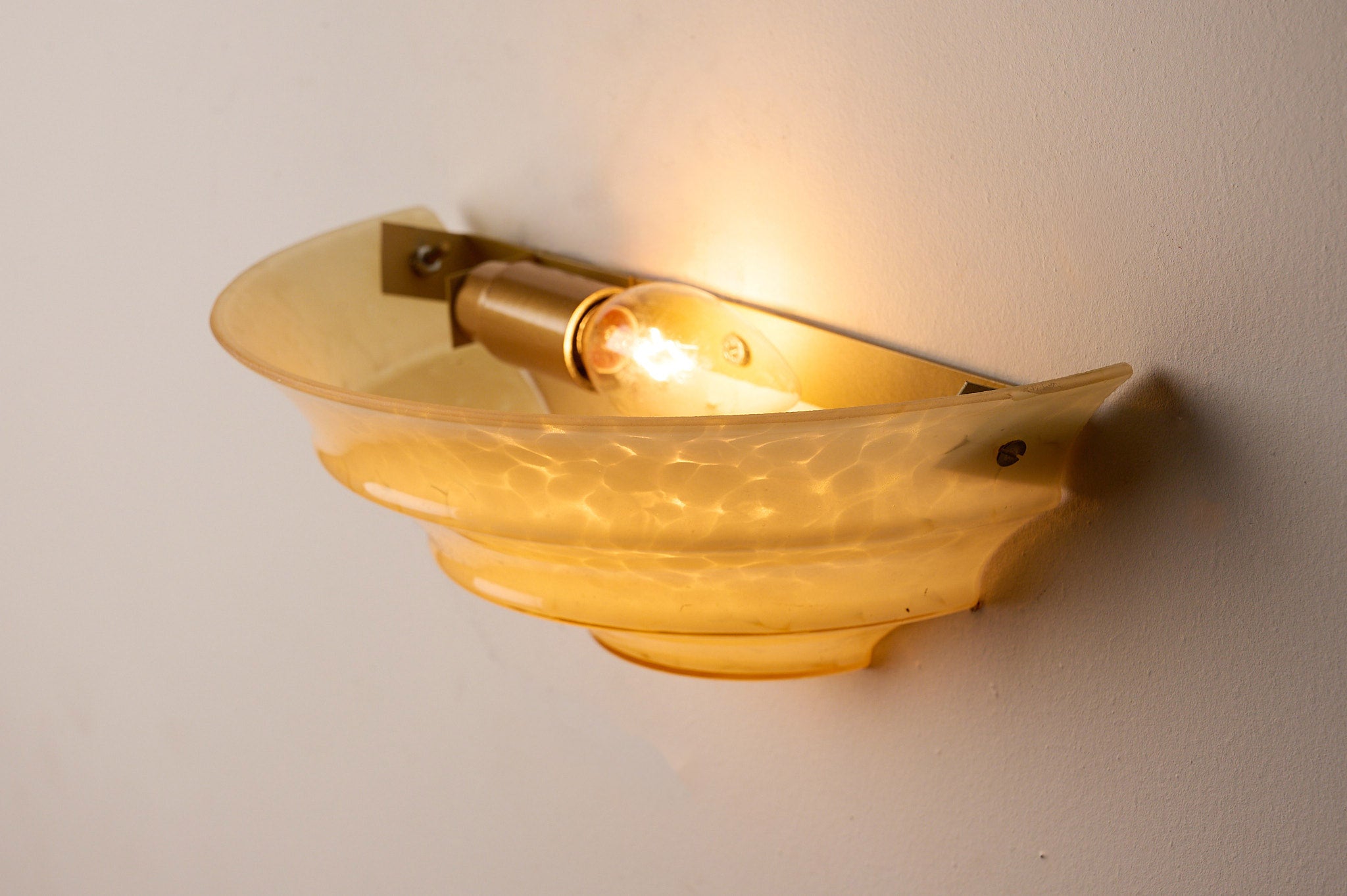 1970s Mid-Century Yellow Marbled Glass Shell Wall Sconce with warm light casting shadows.