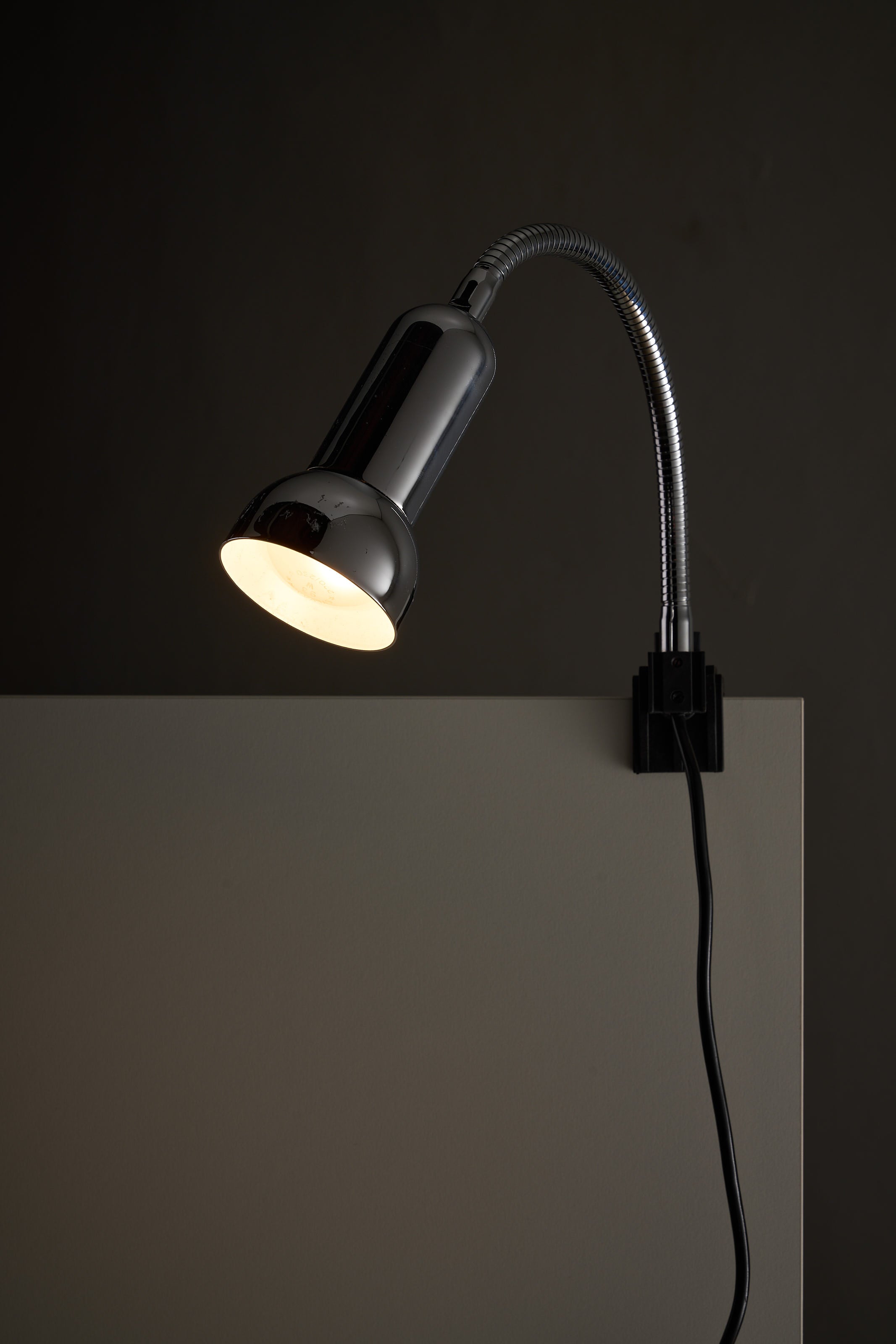 Chrome Clamp Lamp by Cosack mounted on a surface, showcasing its flexible gooseneck and polished chrome design.
