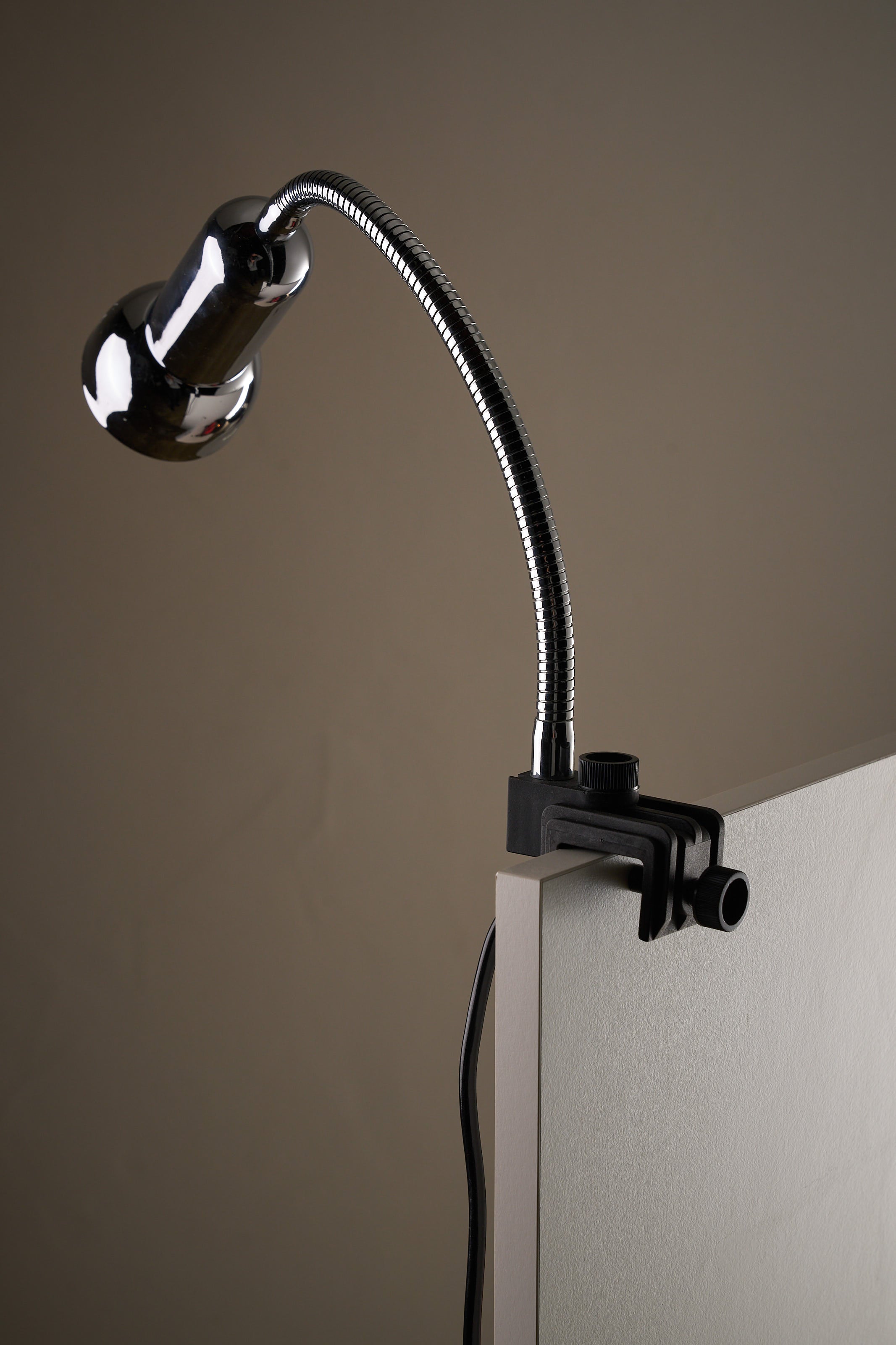Chrome Clamp Lamp by Cosack mounted on a desk with a flexible gooseneck and polished chrome shade.