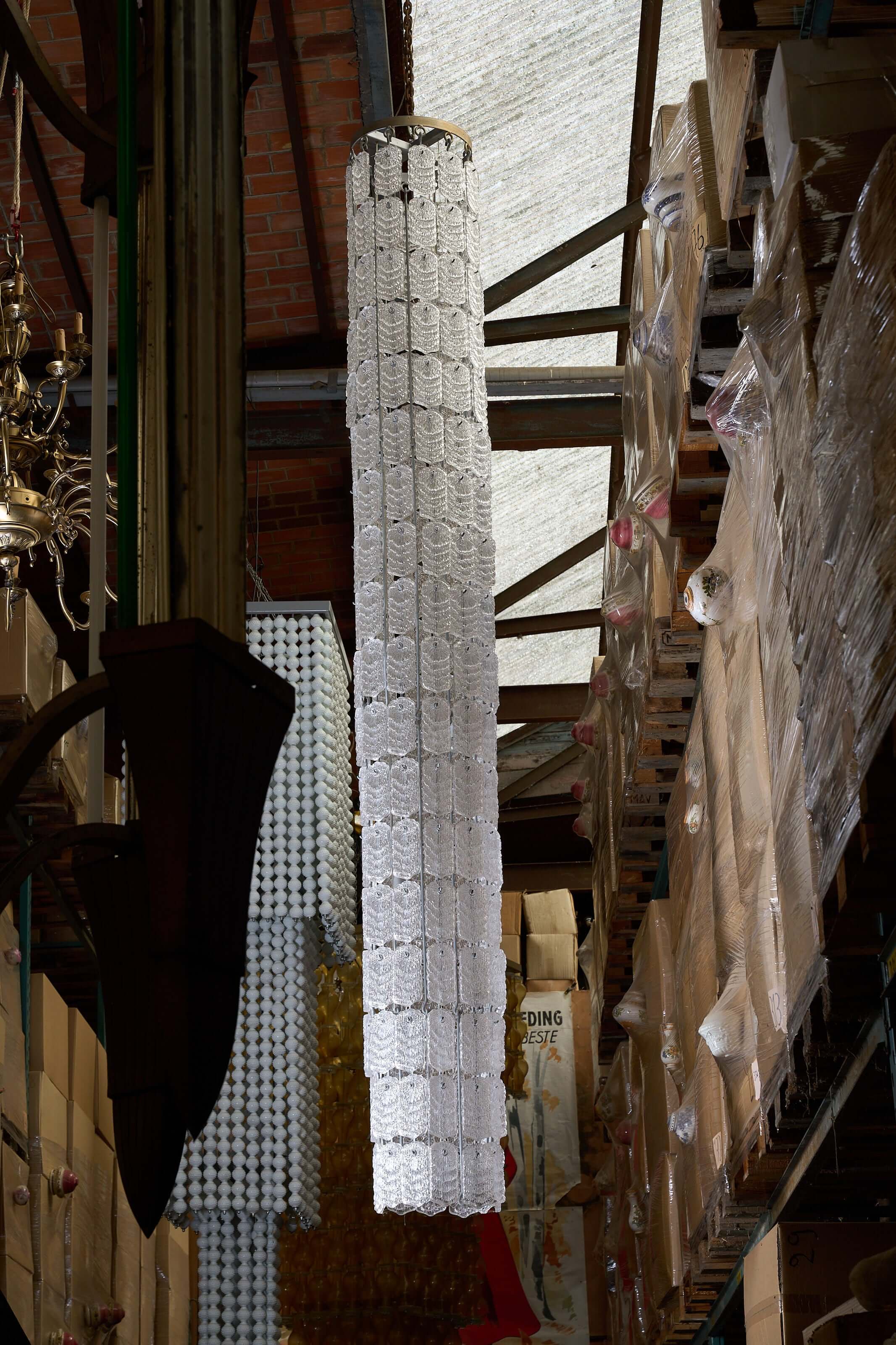 XXL Glass Column Chandelier made of textured glass, showcasing a slender column design in a warehouse setting.