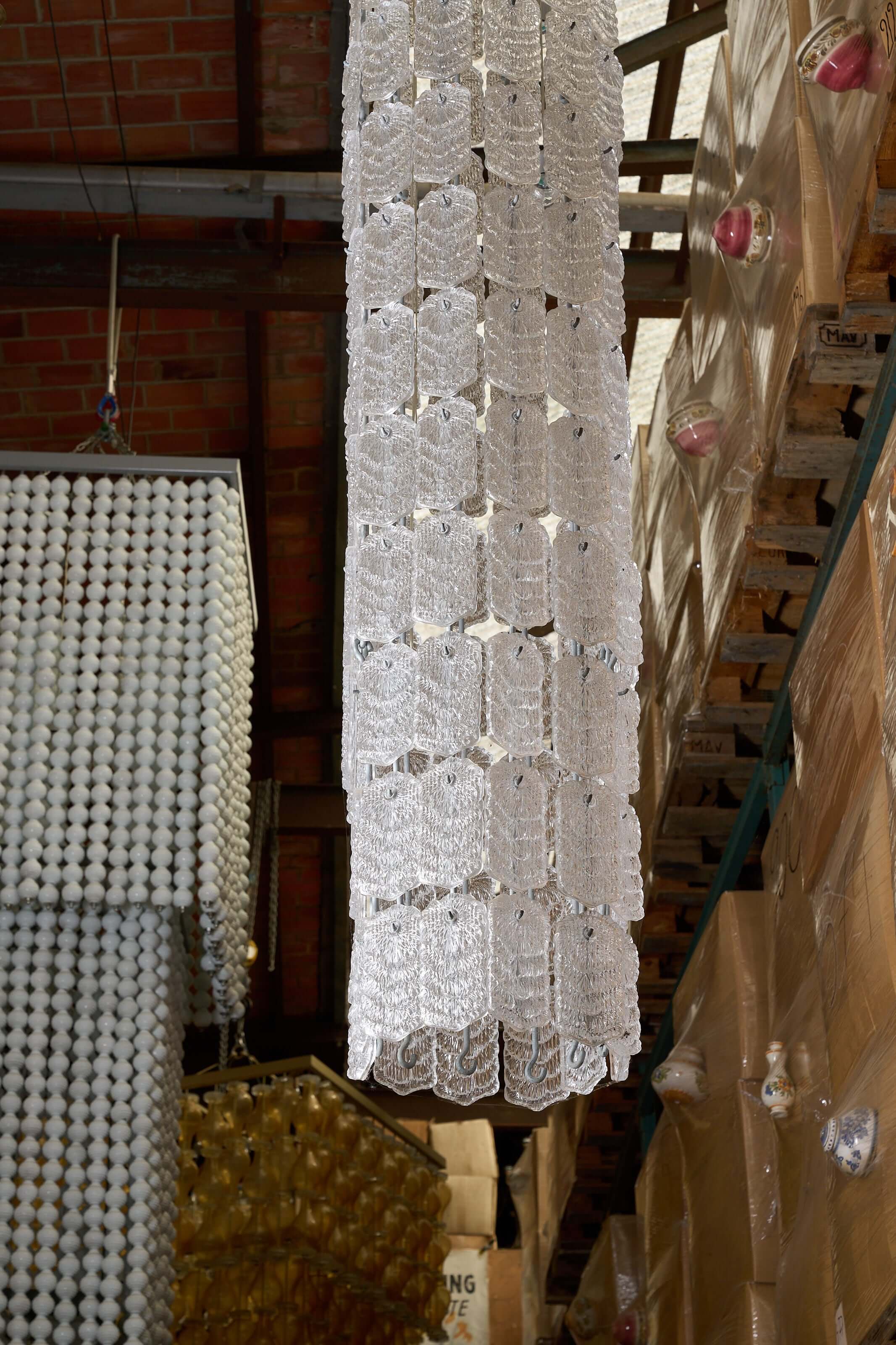 XXL Glass Column Chandelier hanging in a well-lit workspace, showcasing its textured glass design.