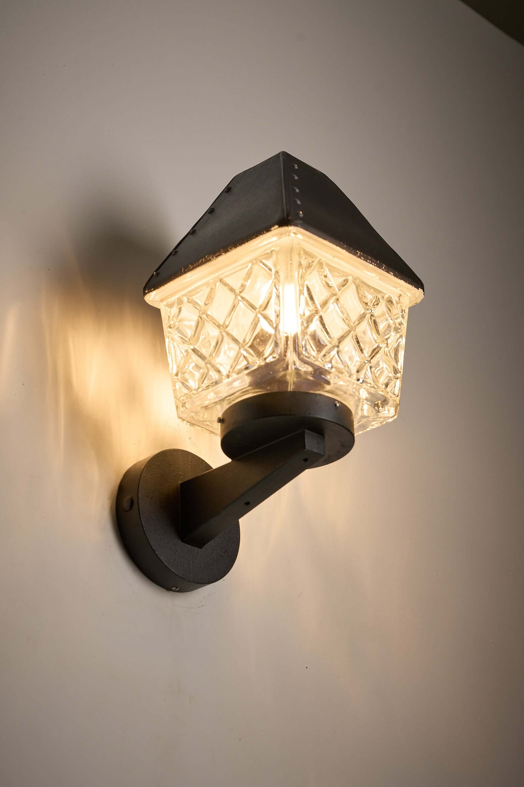 Outdoor Lantern Wall Lamp by Boom Bega mounted on a wall, featuring a diamond-patterned glass diffuser and cast aluminium bracket.