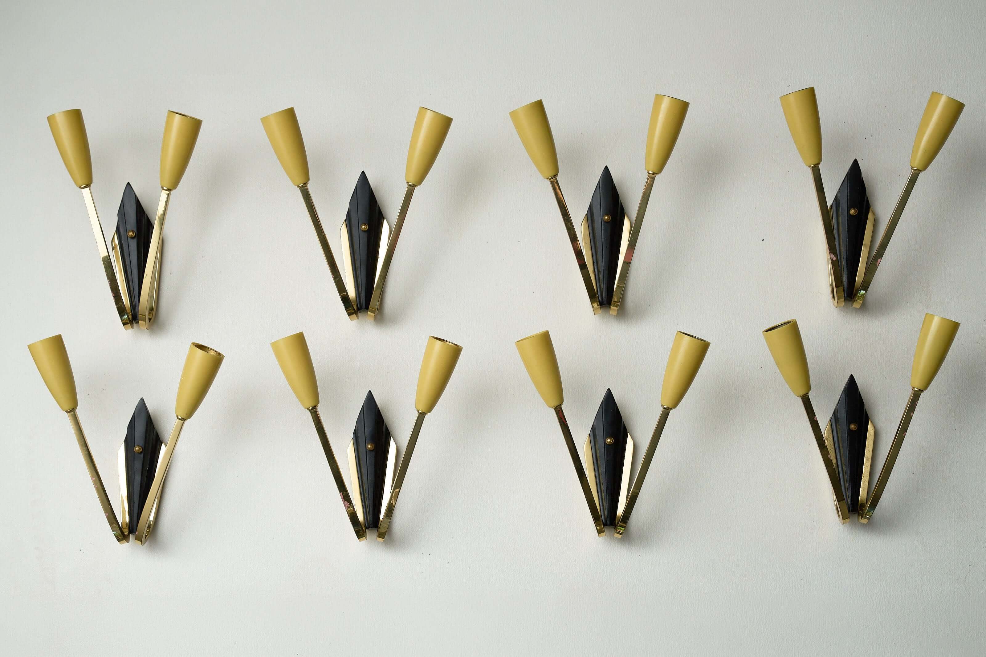 Geometric Brass and Black Wall Lamp, 1950s design with yellow cone-shaped light sockets on a white background.