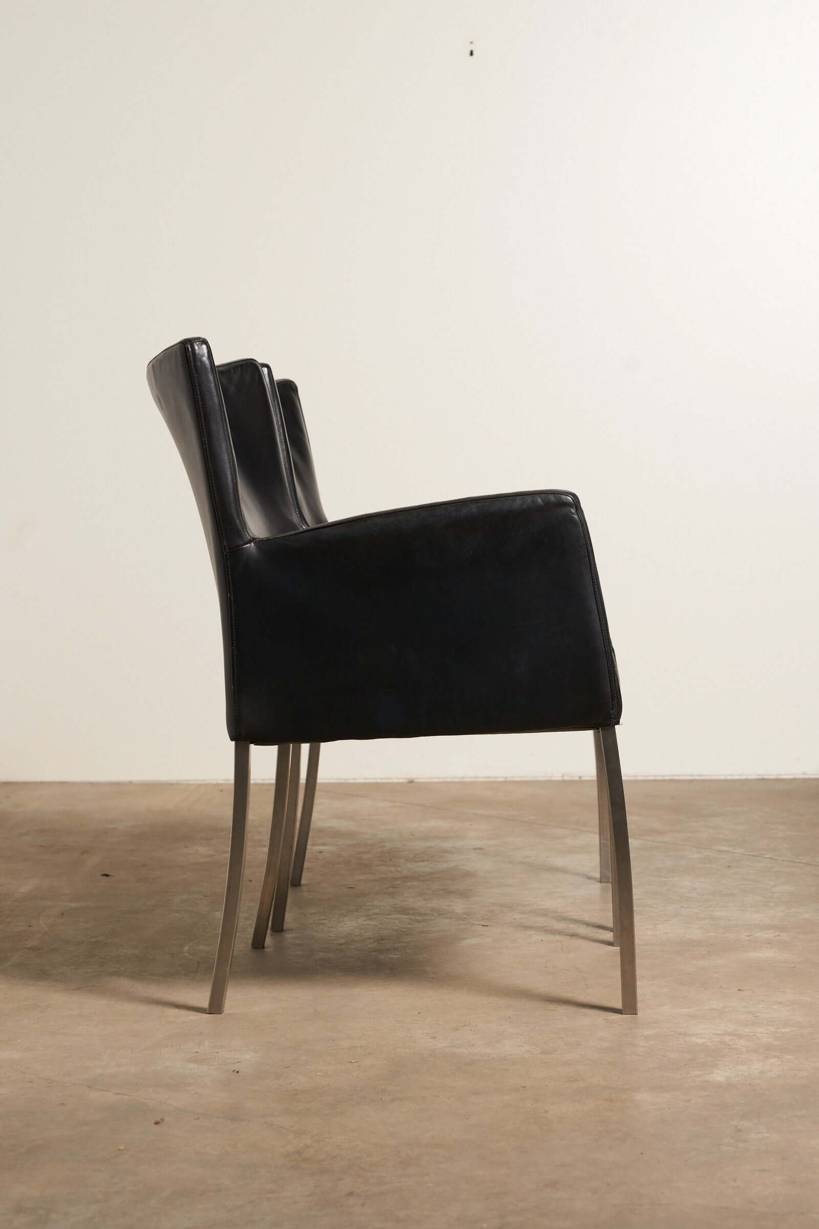 Red or Black Leather Armchairs featuring a sleek black leather dining chair in profile view.