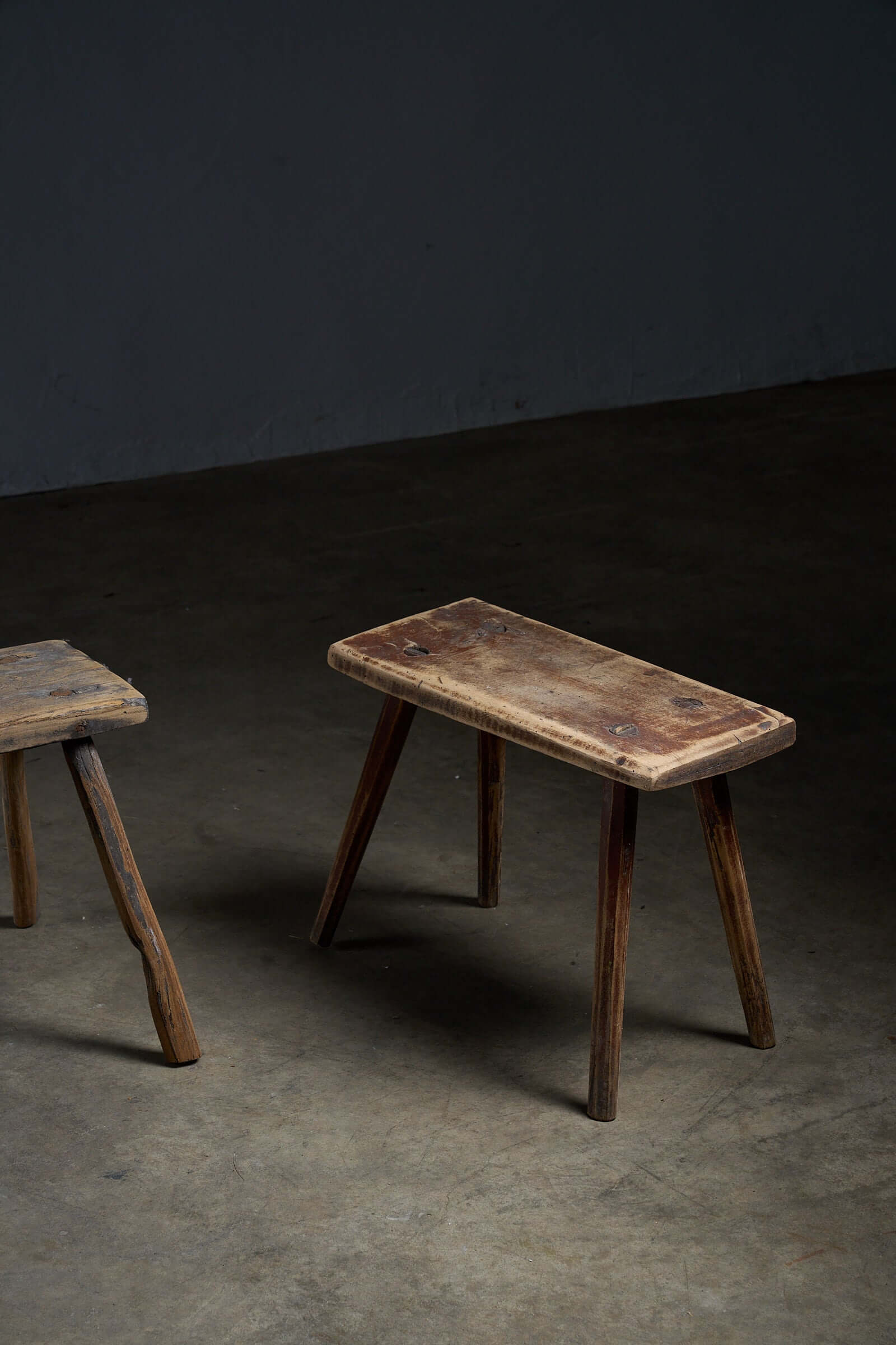 Antique Wooden Stools showcasing unique designs and textured surfaces in a rustic setting.
