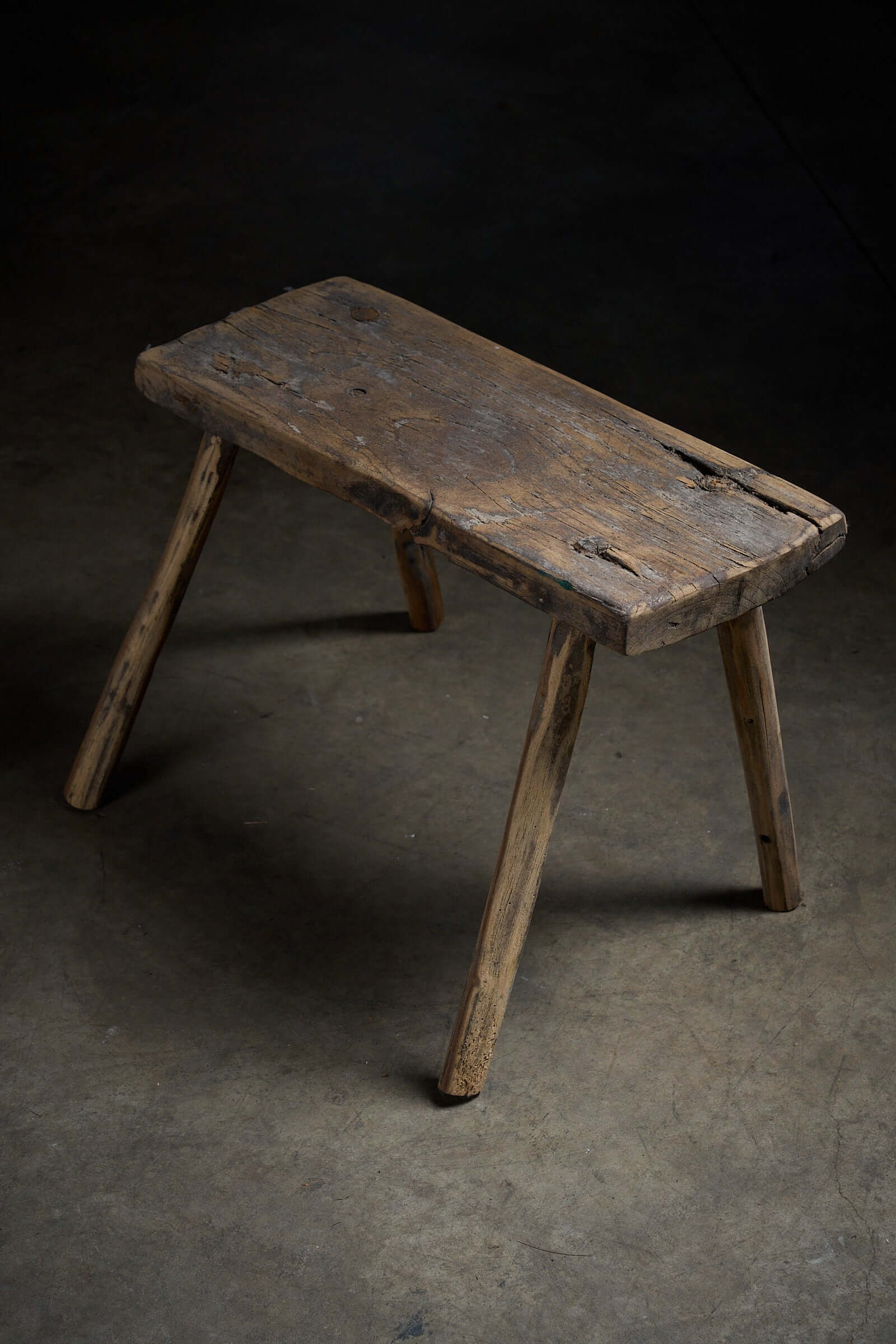 Antique Wooden Stools featuring a rustic, textured wooden seat and slender legs, perfect as a side table.