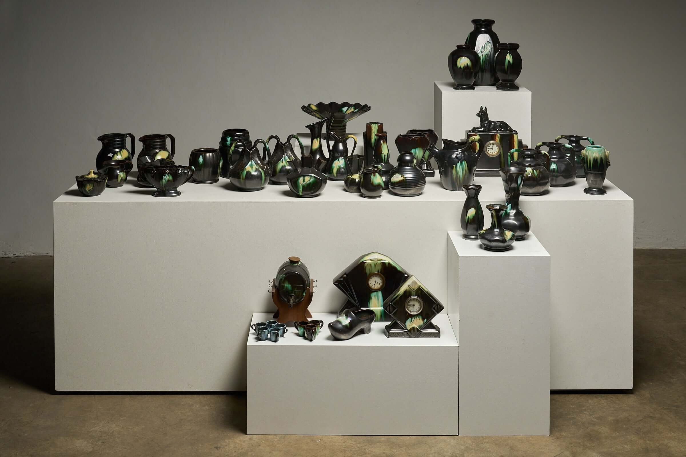 Large Collection of Belgian Art Deco Drip Glaze Ceramics 1920s displayed on white pedestals.