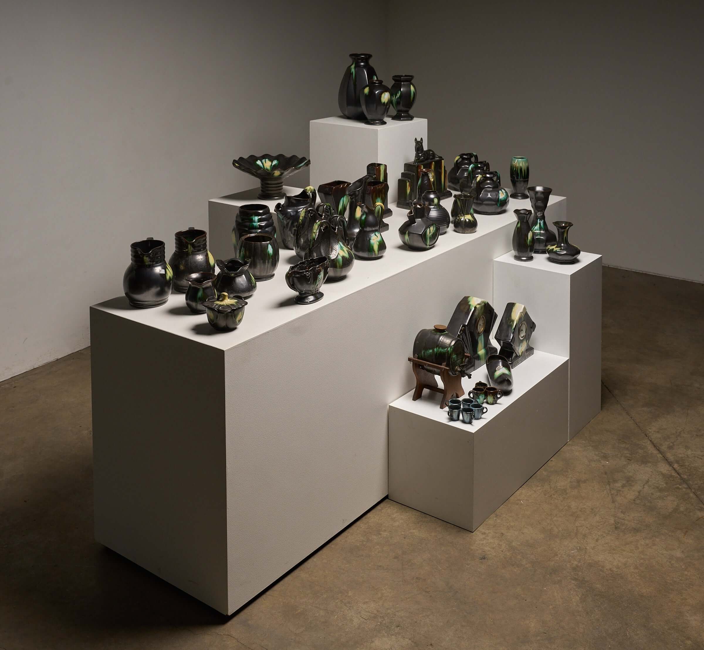 Large Collection of Belgian Art Deco Drip Glaze Ceramics 1920s displayed on white pedestals in various shapes and sizes.