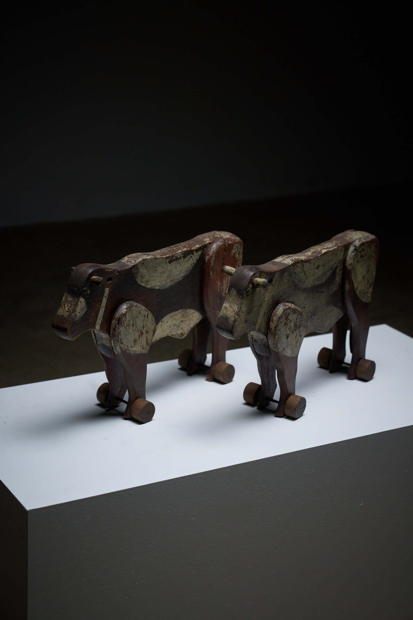 Pair of Antique Articulated Wooden Cow Pull Toys on display, showcasing their distressed antique condition and folk art charm.