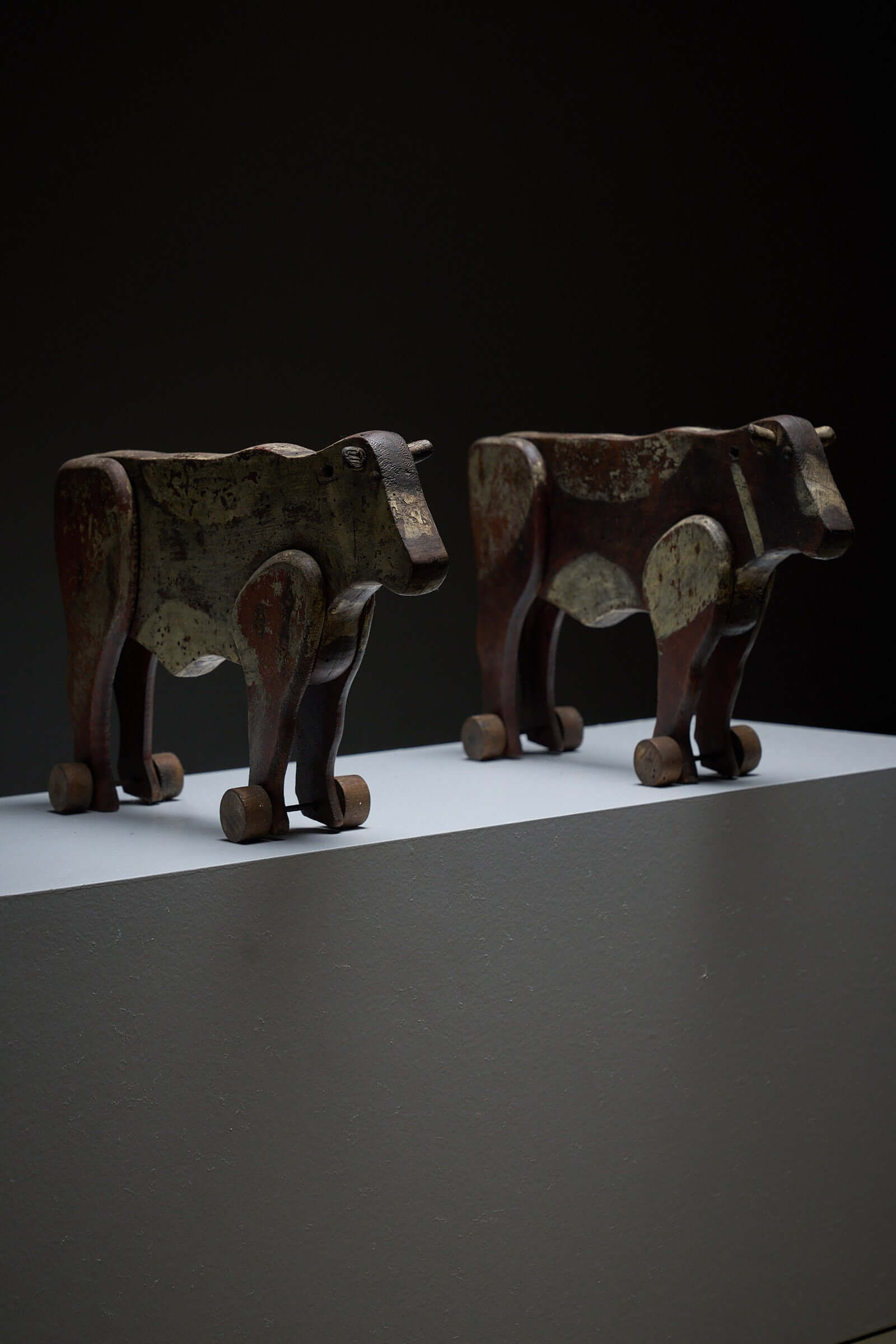 Pair of Antique Articulated Wooden Cow Pull Toys displayed on a shelf in rustic decor.