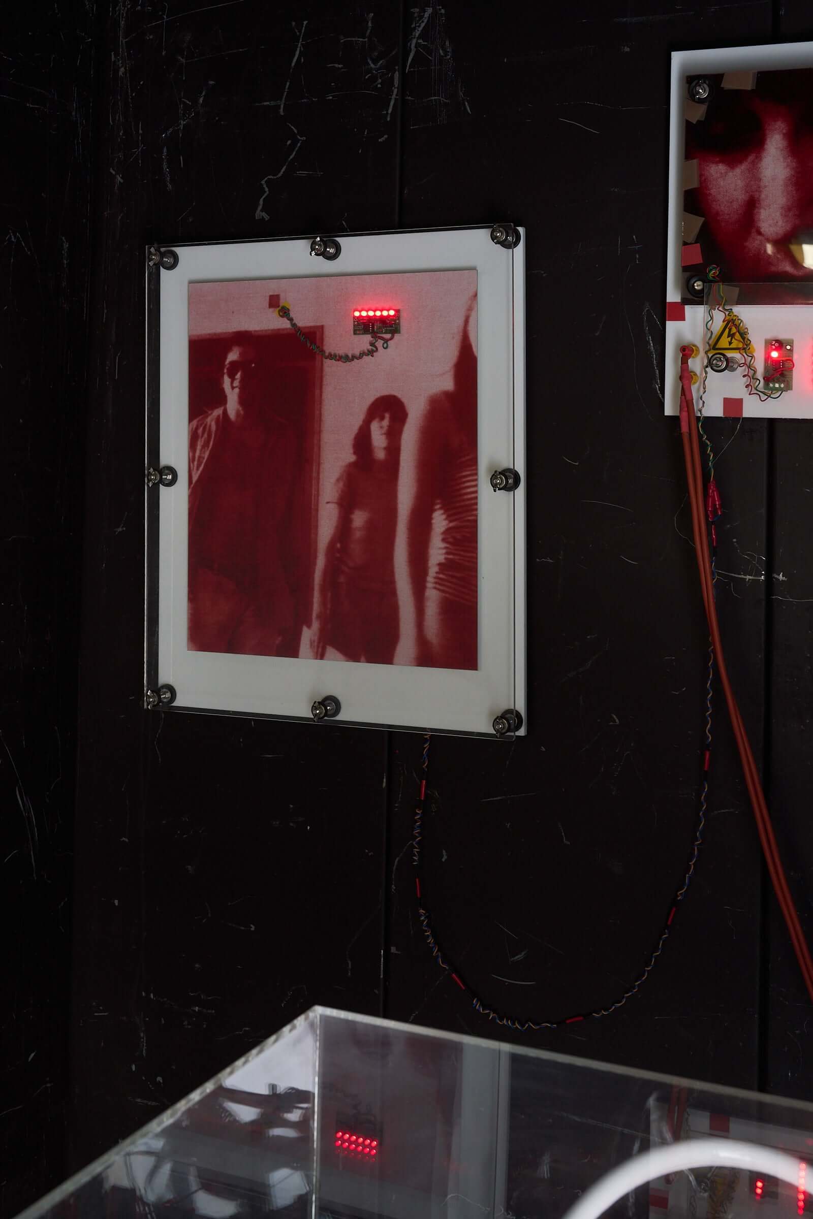 The Ulrike Meinhof Shopping Bag Installation by Eduard Van Giel (2017) featuring red-tinted artwork on wall.