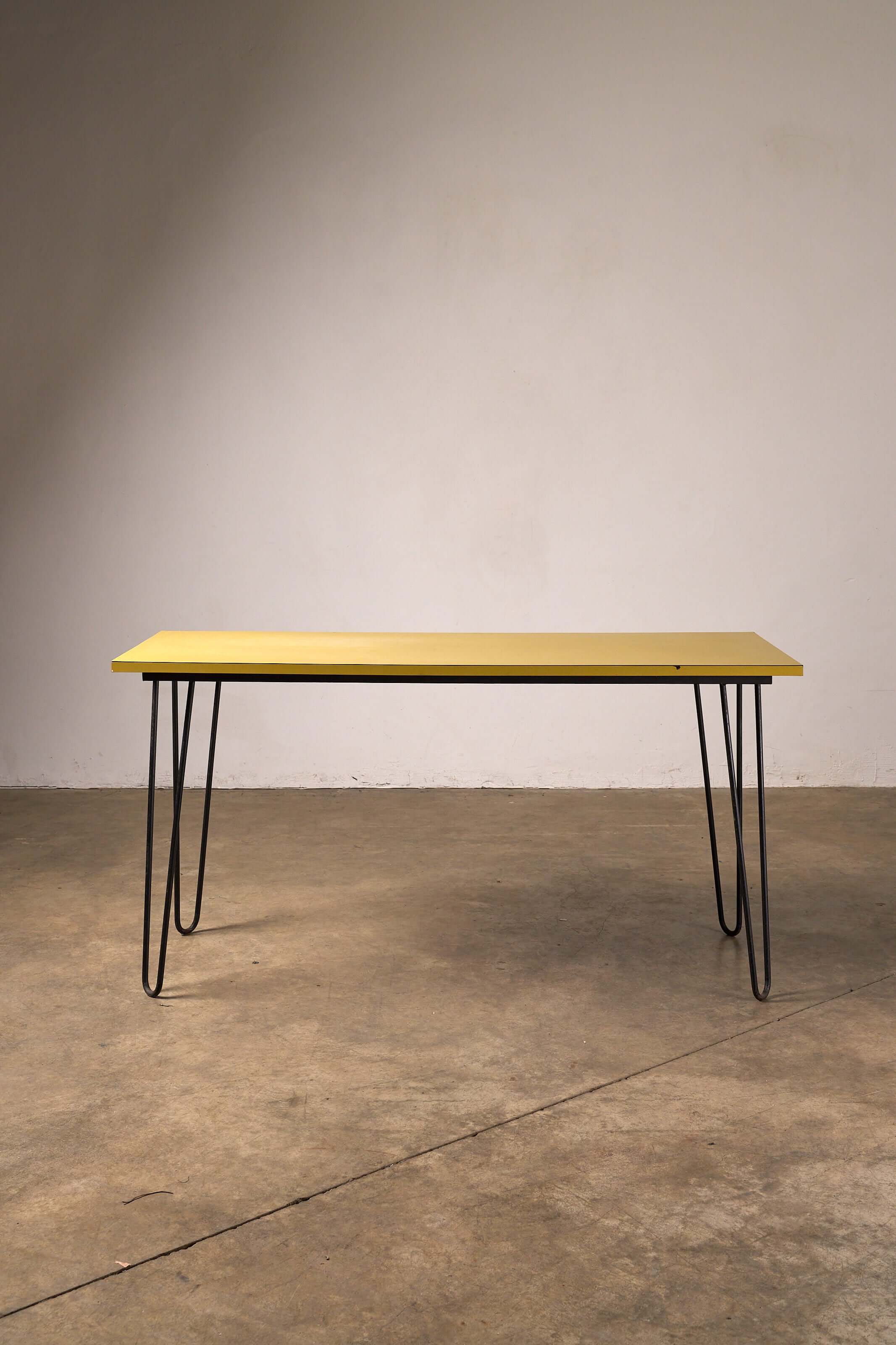 Mid-Century Yellow Console or Desk with textured yellow laminate top and black hairpin legs on a concrete floor.