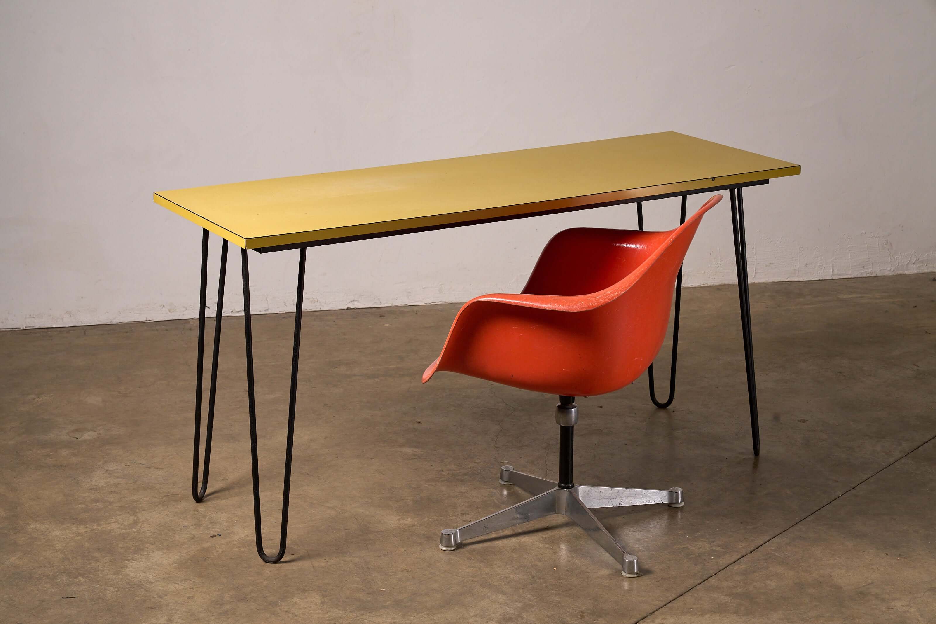 Mid-Century Yellow Console or Desk with black hairpin legs and red chair in a minimalist setting.