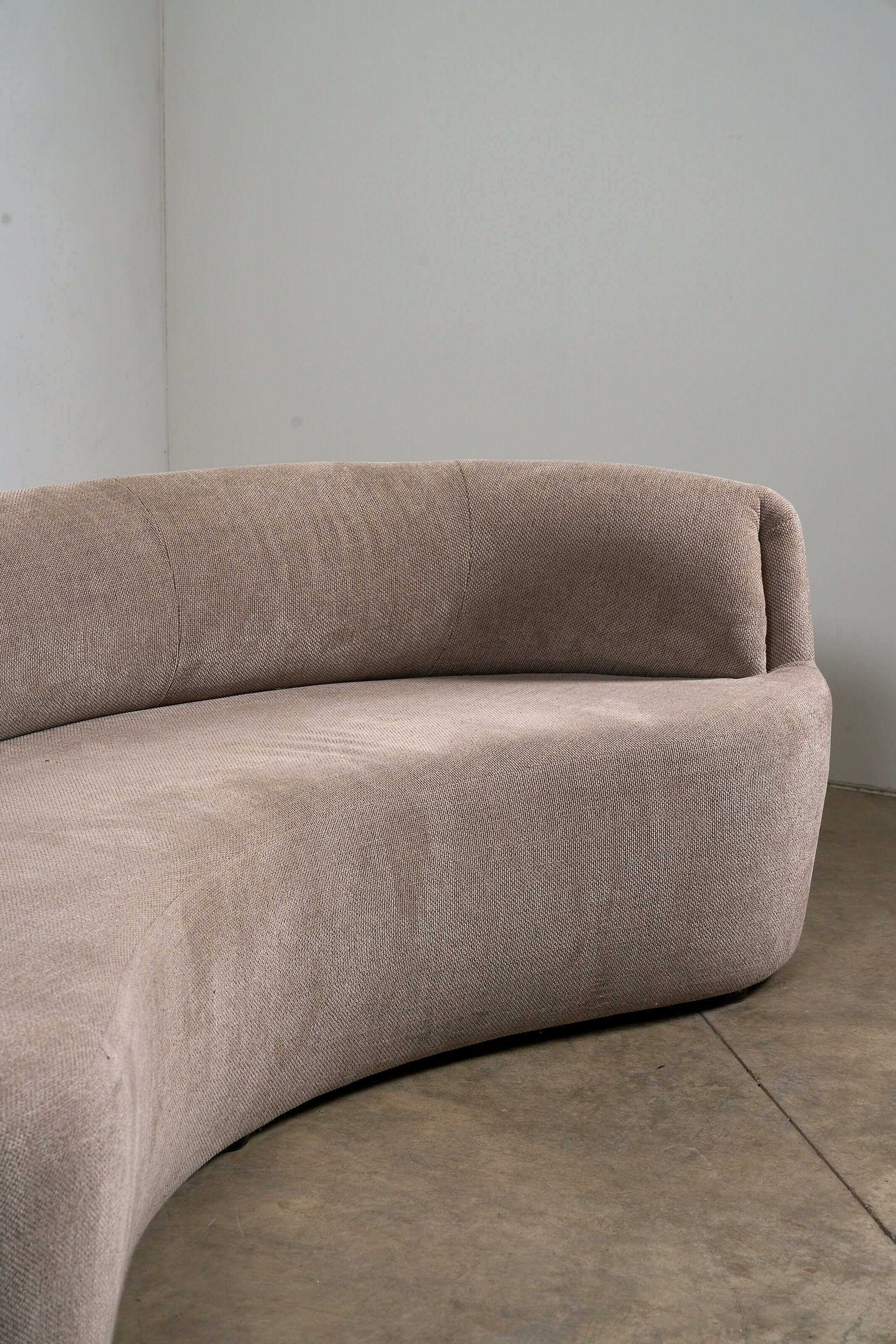 Close-up of the Organic Modern Curved Fabric Sofa featuring sculptural lines in textured woven beige fabric.