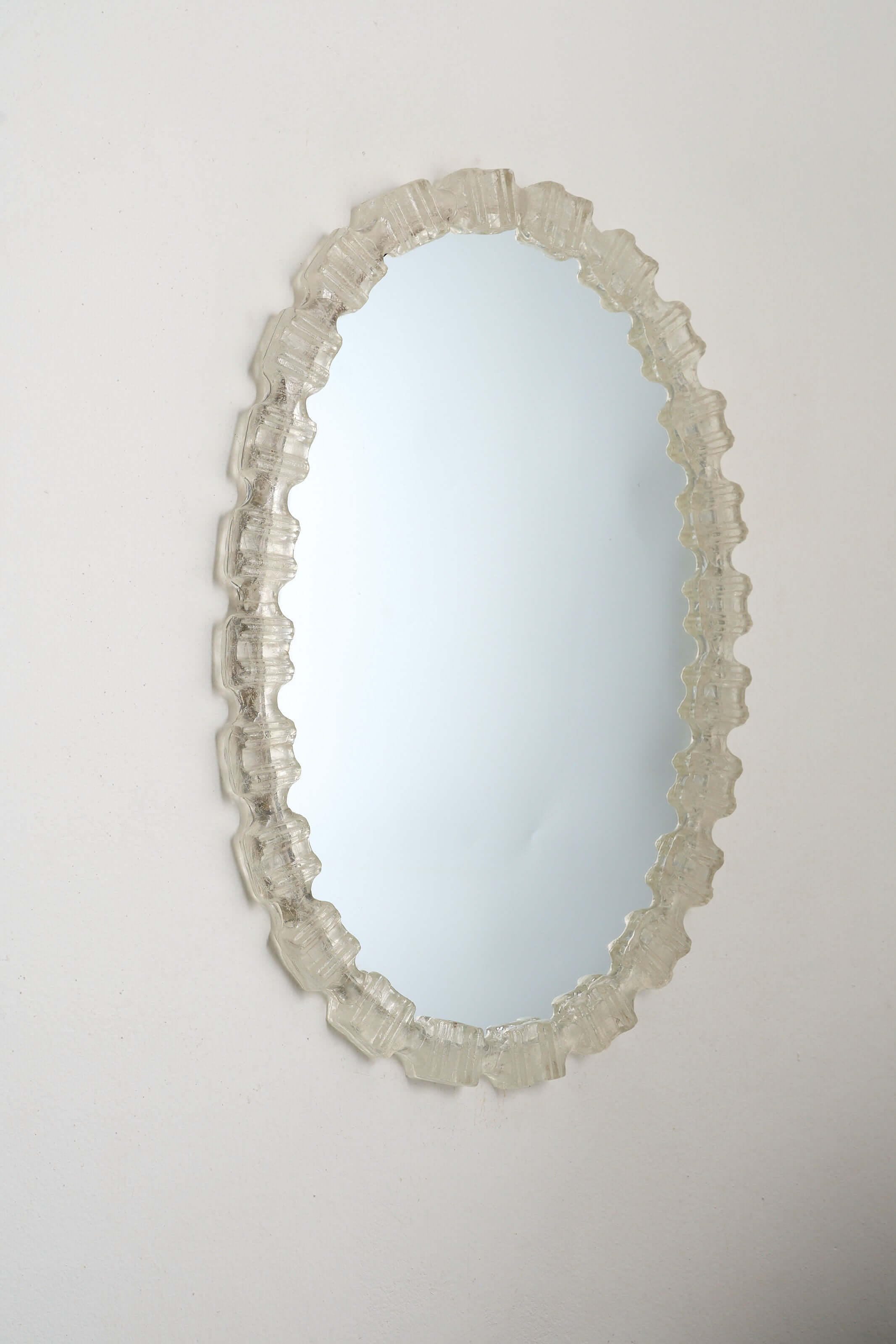 Oval Cast Plexiglass Mirror framed in textured acrylic with a geometric edge pattern.