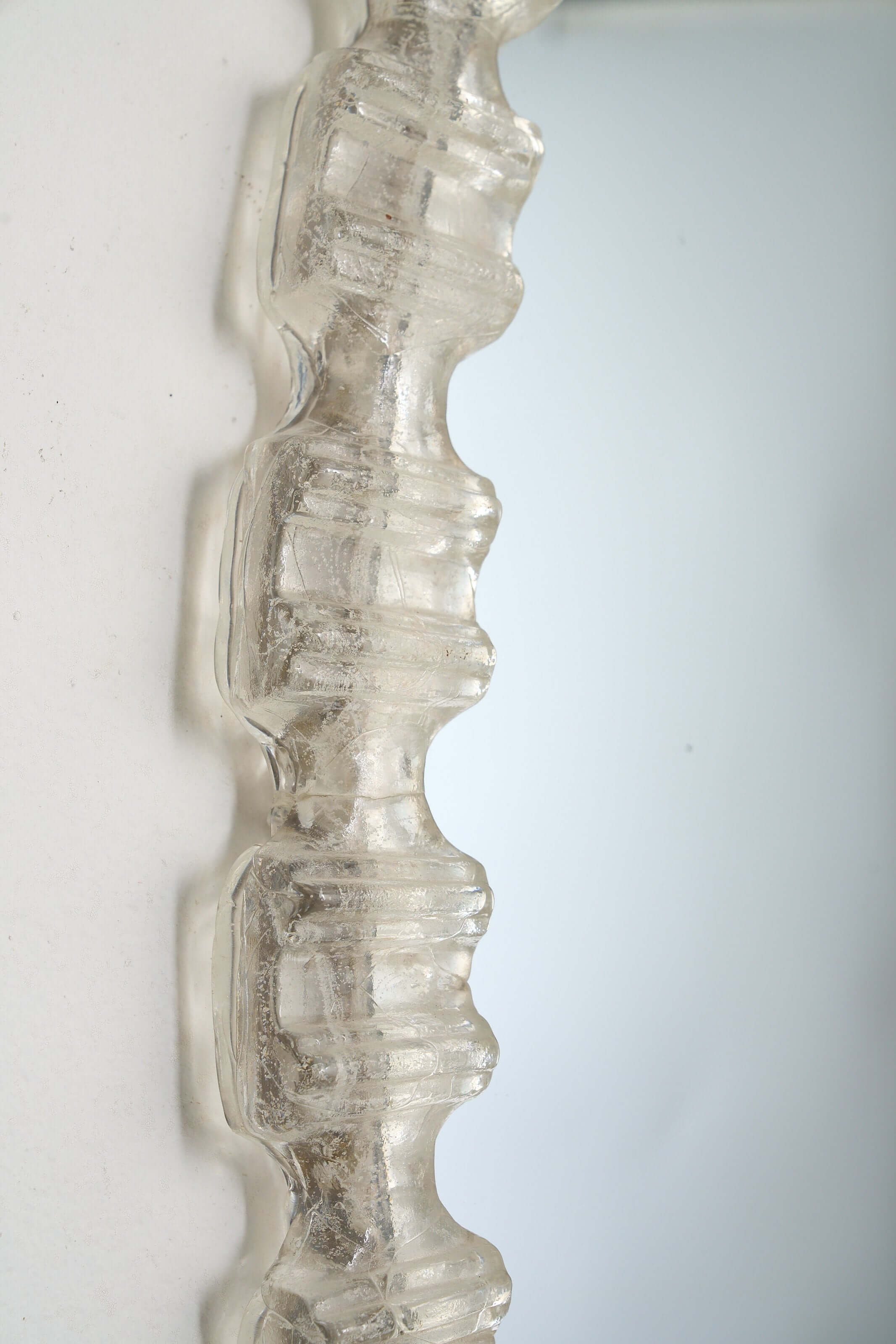 Detail of the Oval Cast Plexiglass Mirror showcasing its geometric texture and clear plexiglass frame.