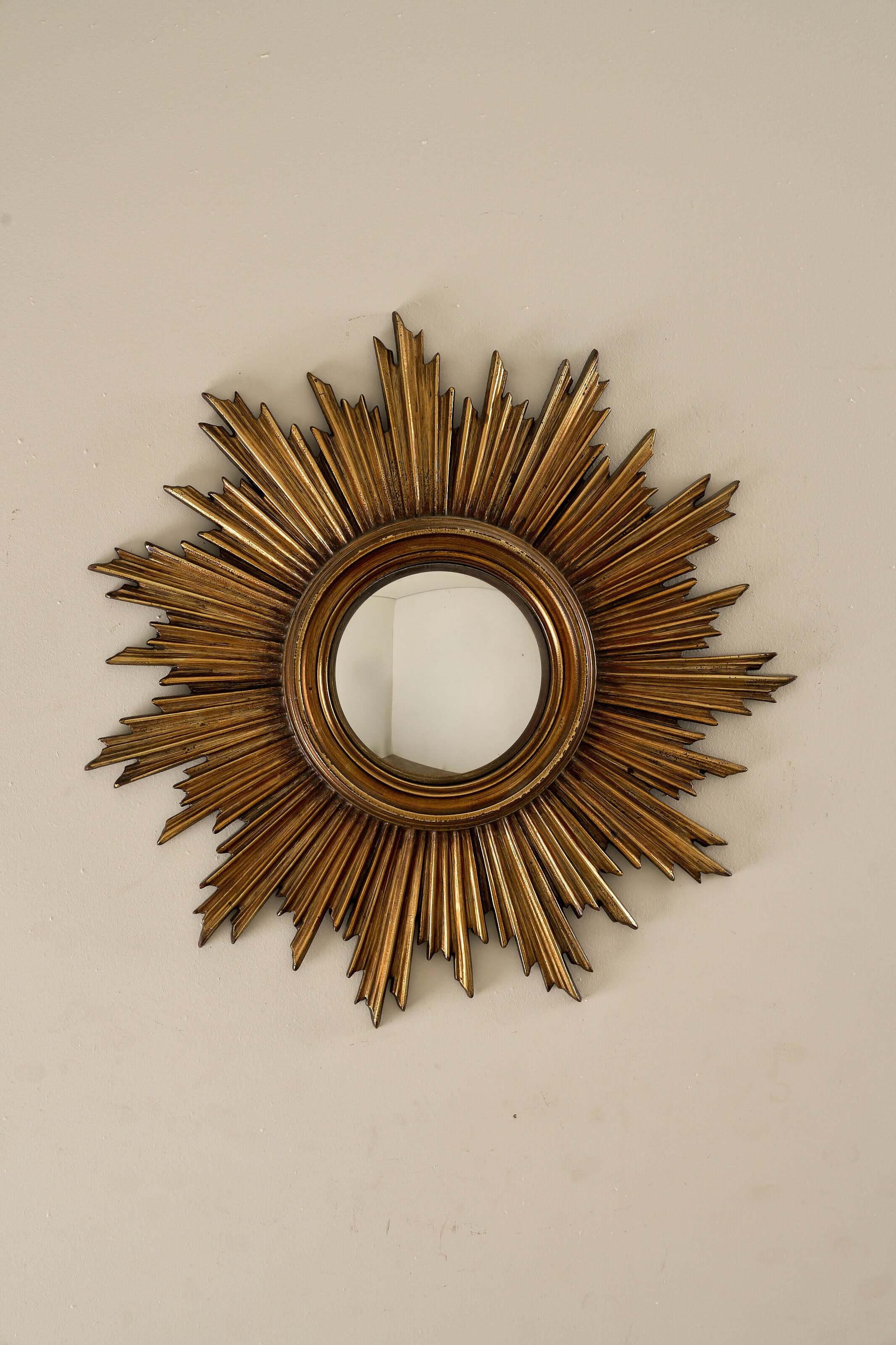 Mid-Century Gilt Wood Sunburst Mirror, 1960s with jagged rays and central convex mirror mounted on a wall.