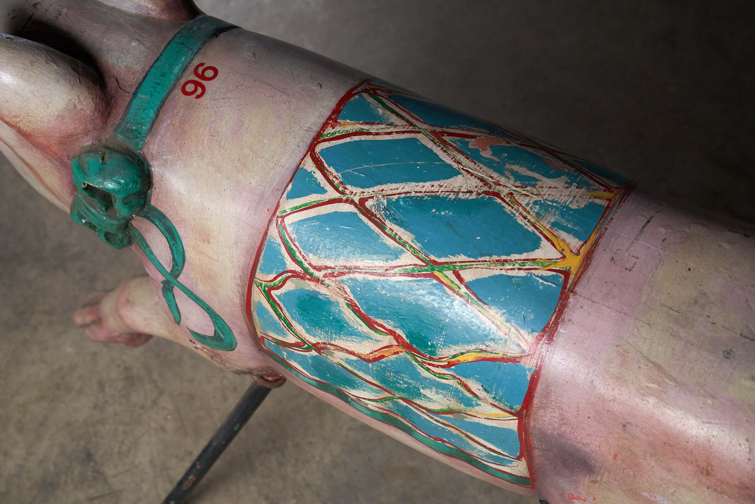 Close-up of the polychrome painted detail of a Carved Wooden Carousel Pig Figure, showcasing vibrant colors and unique patterns.