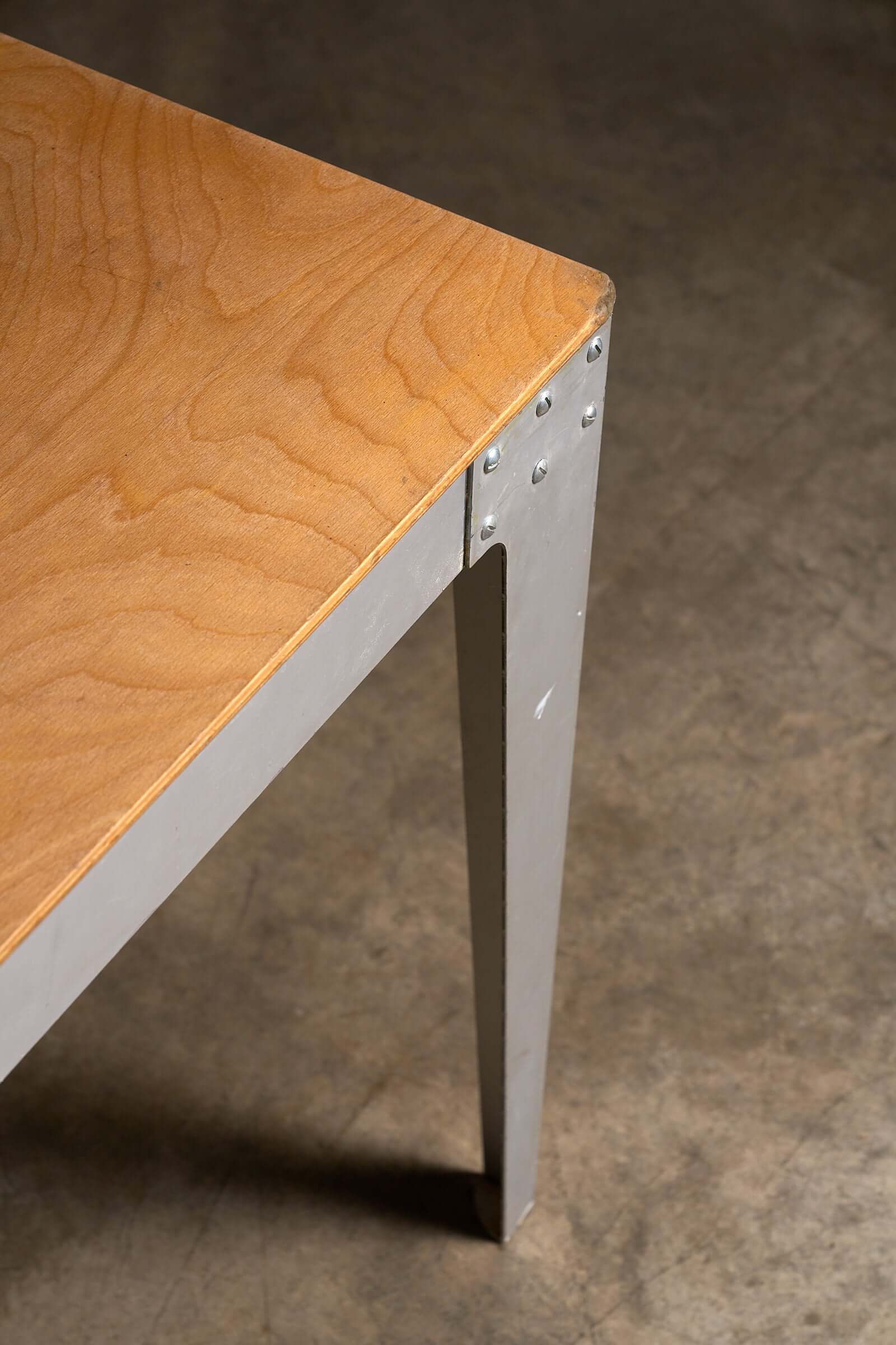 Close-up of the Piet Hein Eek Industrial Aluminium and Plywood Dining Table showcasing plywood top and metal leg.