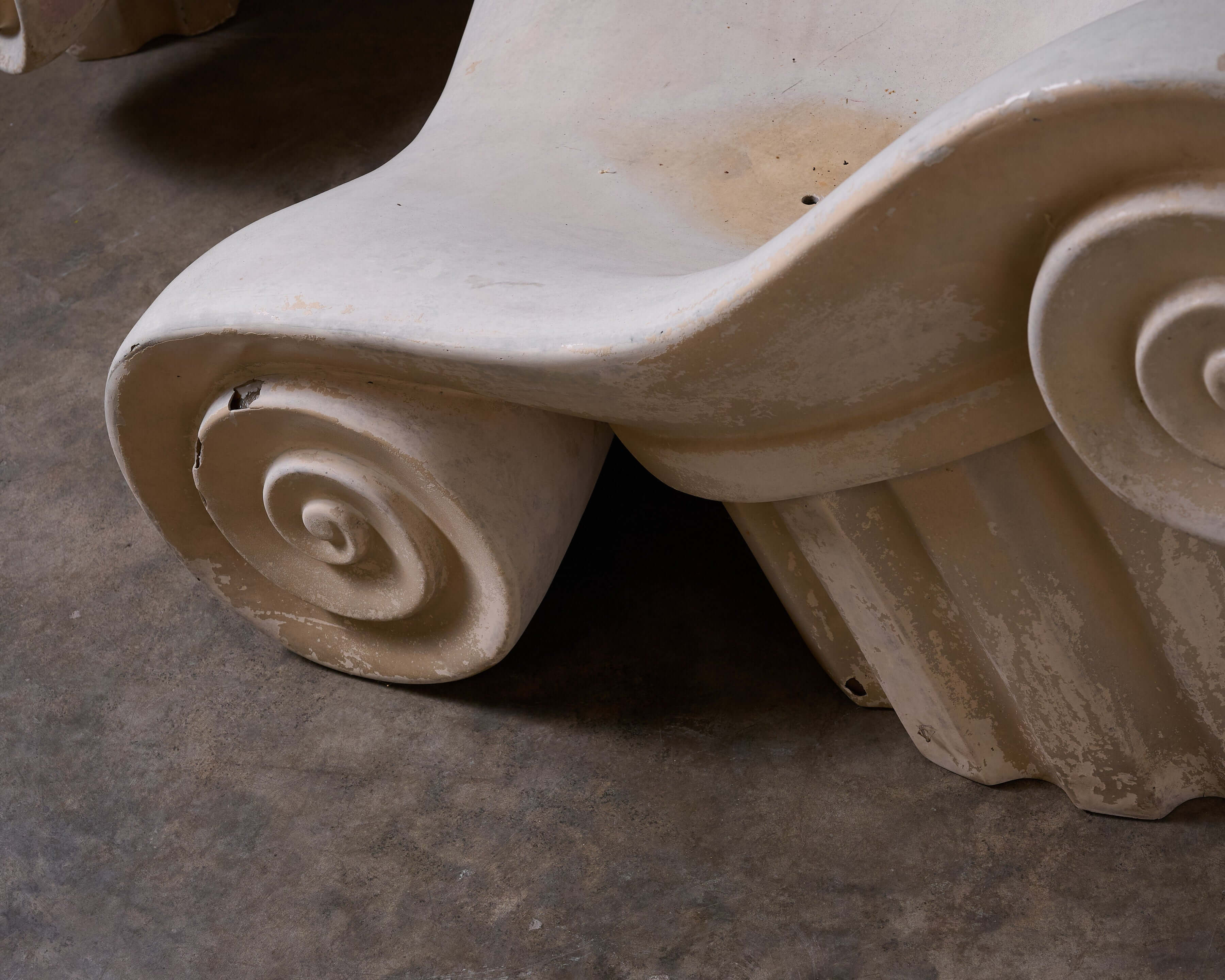 Detail of the elegant base design of the 'Capitello' Chair with Ottoman, inspired by ancient Greek architecture.