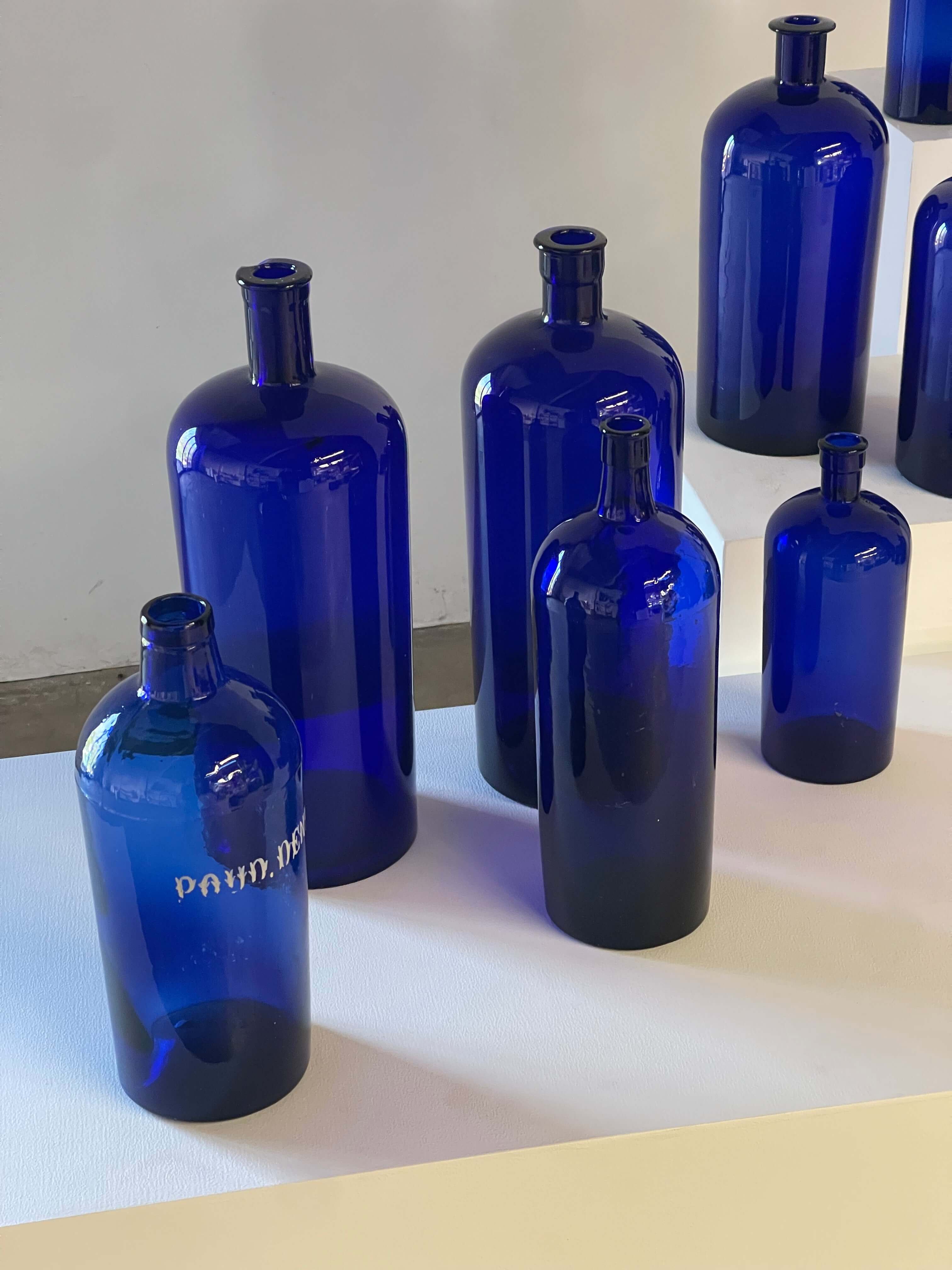 Collection of Antique Cobalt Blue Essence and Apothecary Bottles displayed on a white surface.
