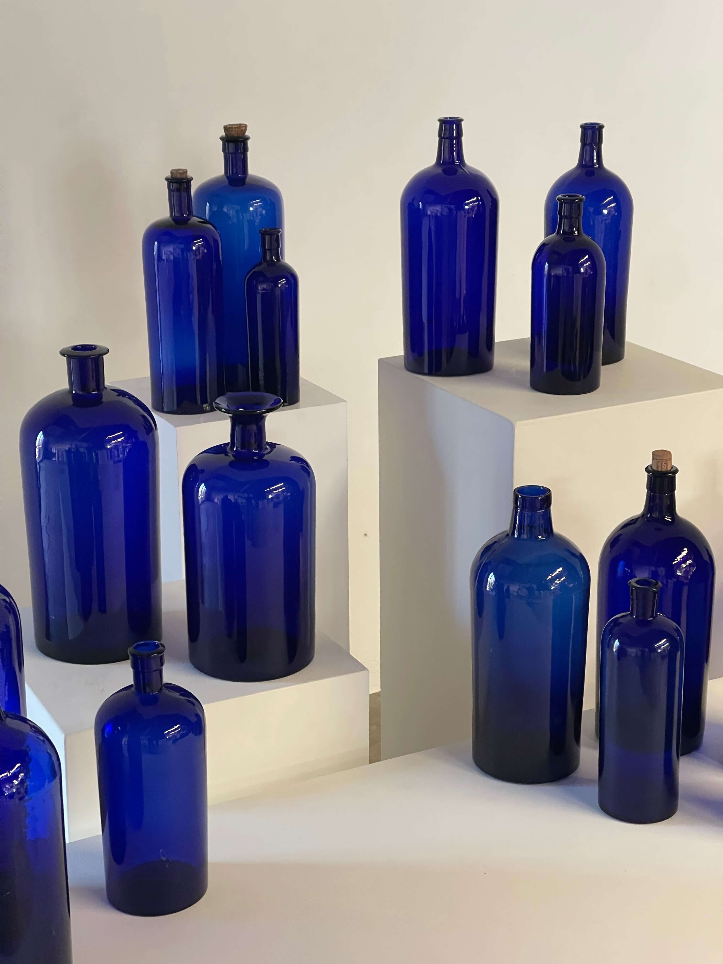 Collection of Antique Cobalt Blue Essence and Apothecary Bottles displayed prominently.