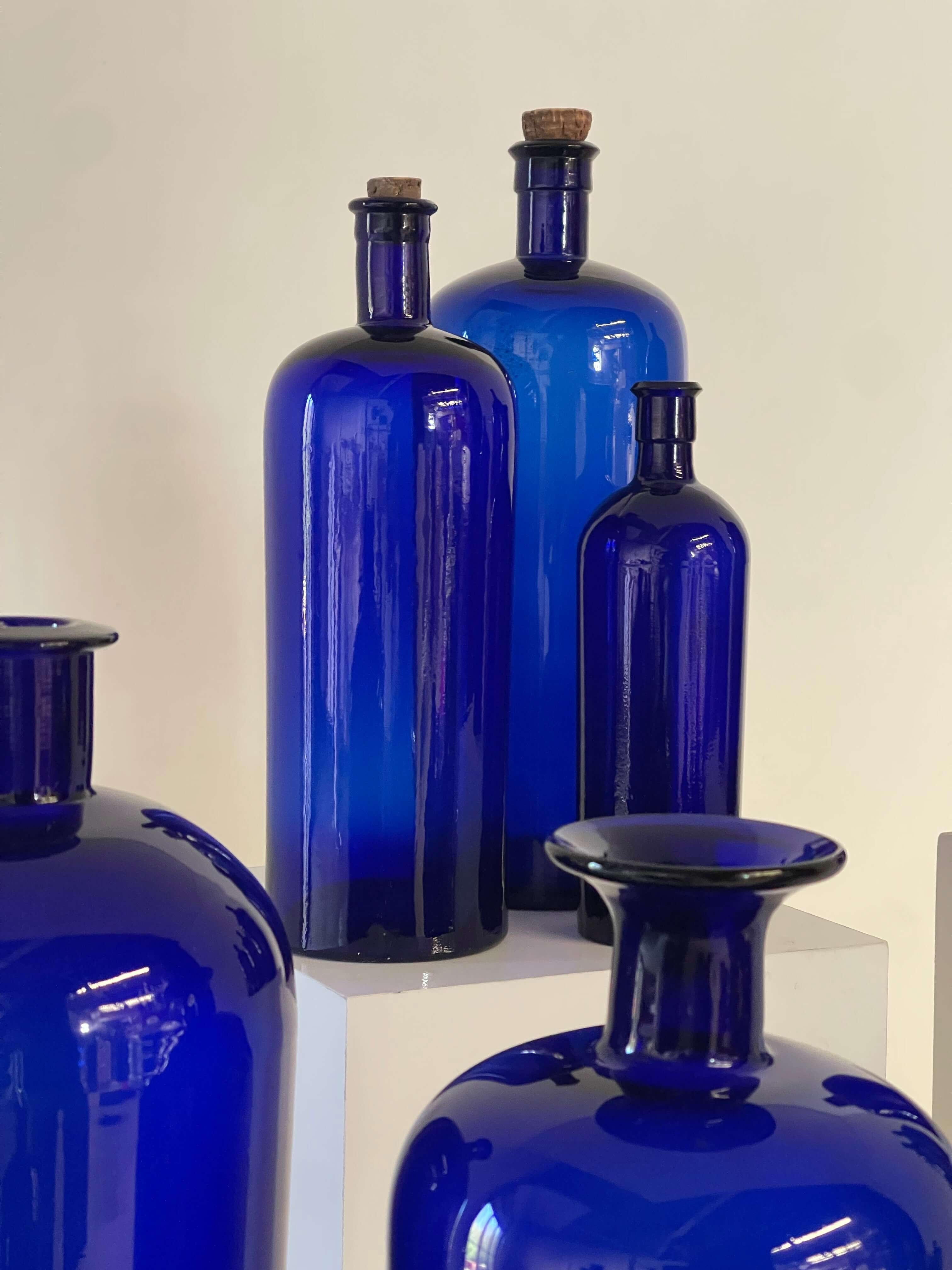 Collection of Antique Cobalt Blue Essence and Apothecary Bottles arranged elegantly against a neutral background.