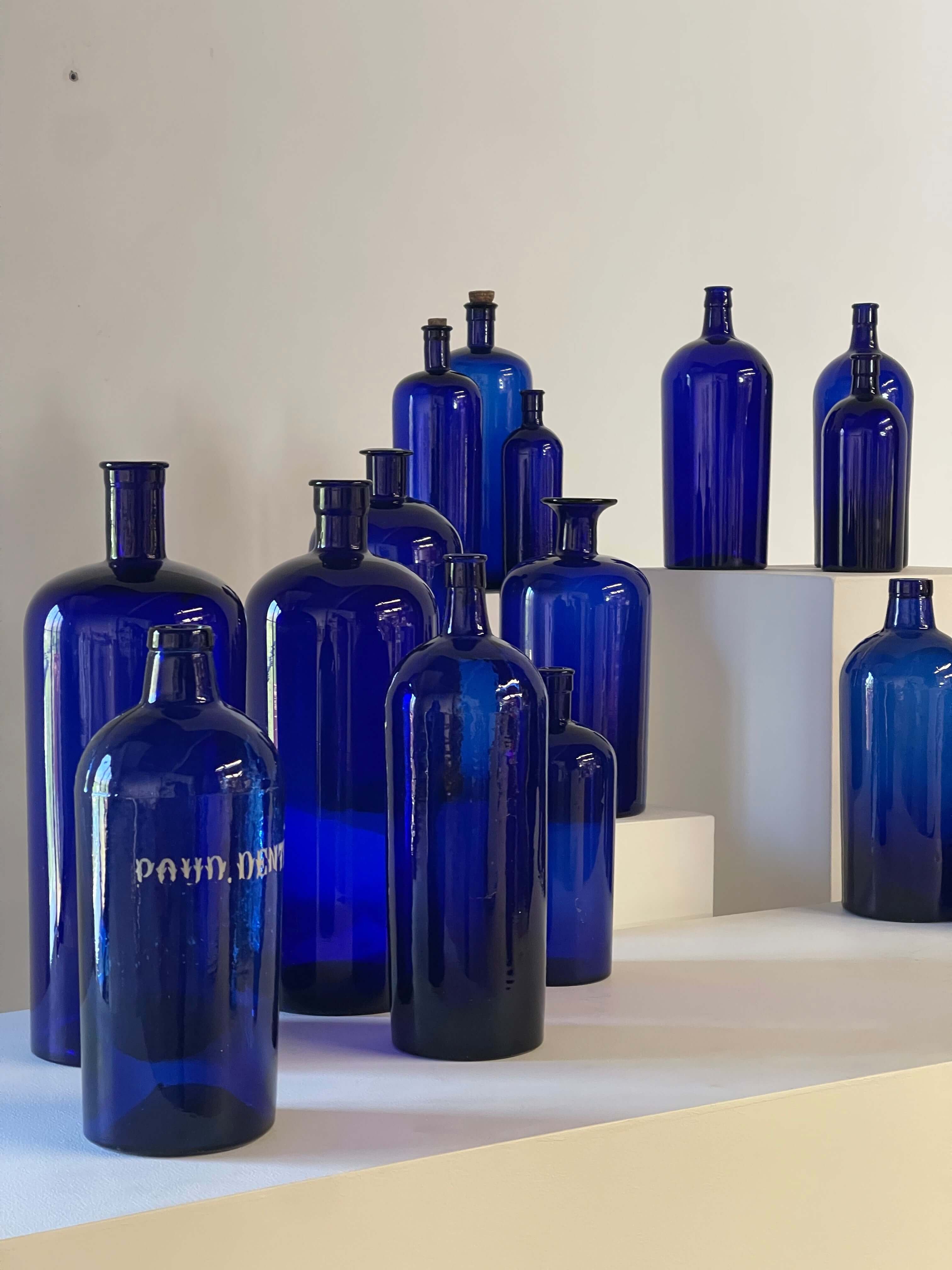 Collection of Antique Cobalt Blue Essence and Apothecary Bottles displayed in a modern setting.