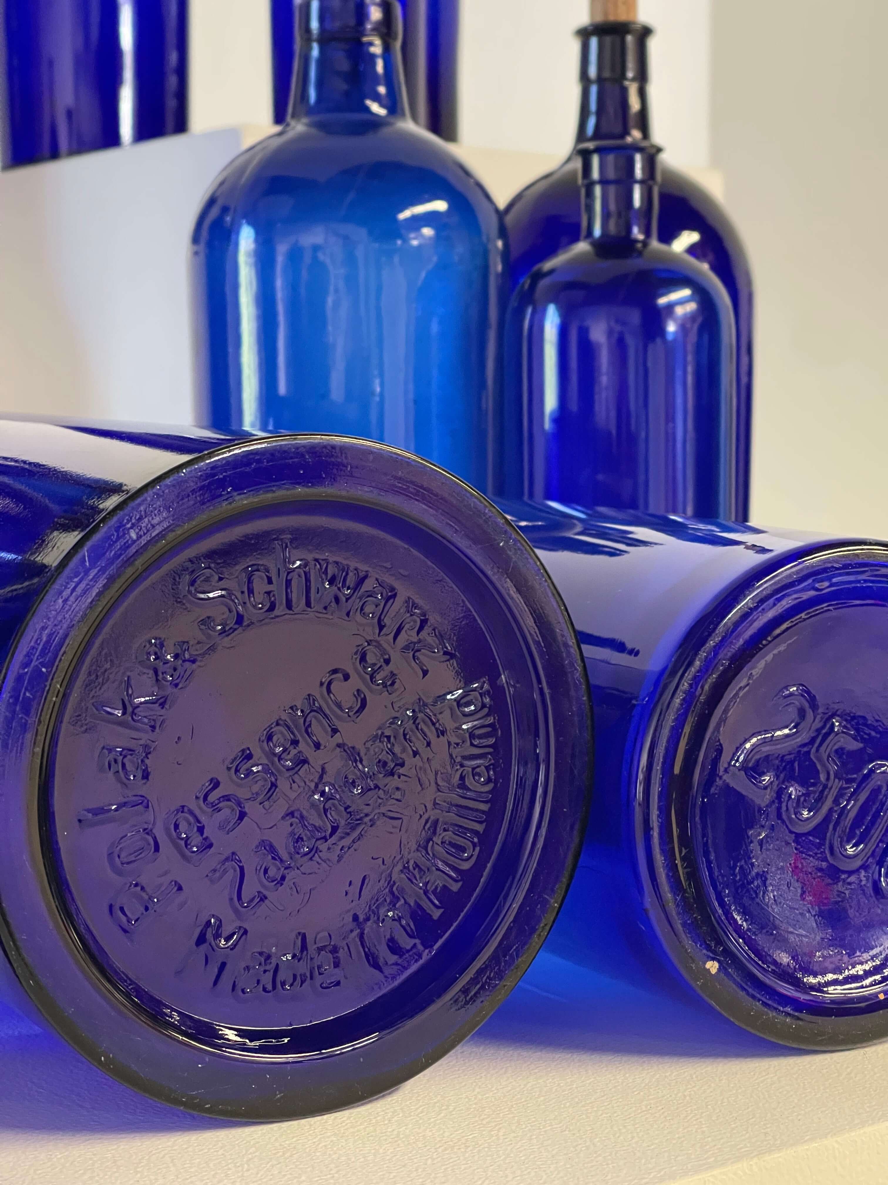 Collection of Antique Cobalt Blue Essence and Apothecary Bottles featuring Polak & Schwarz embossed designs.