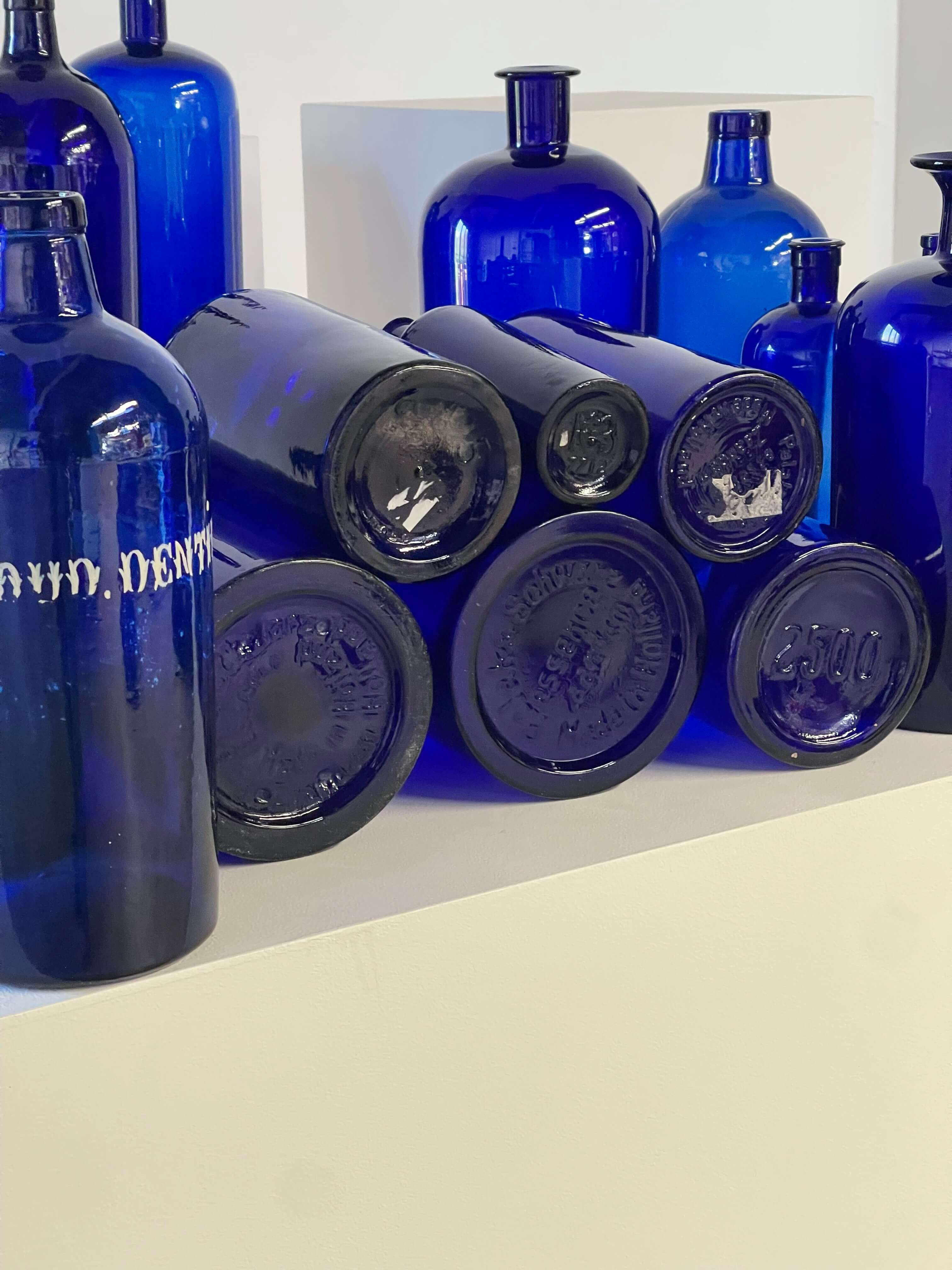 Collection of Antique Cobalt Blue Essence and Apothecary Bottles featuring vintage hand-painted jars and industrial bottles.